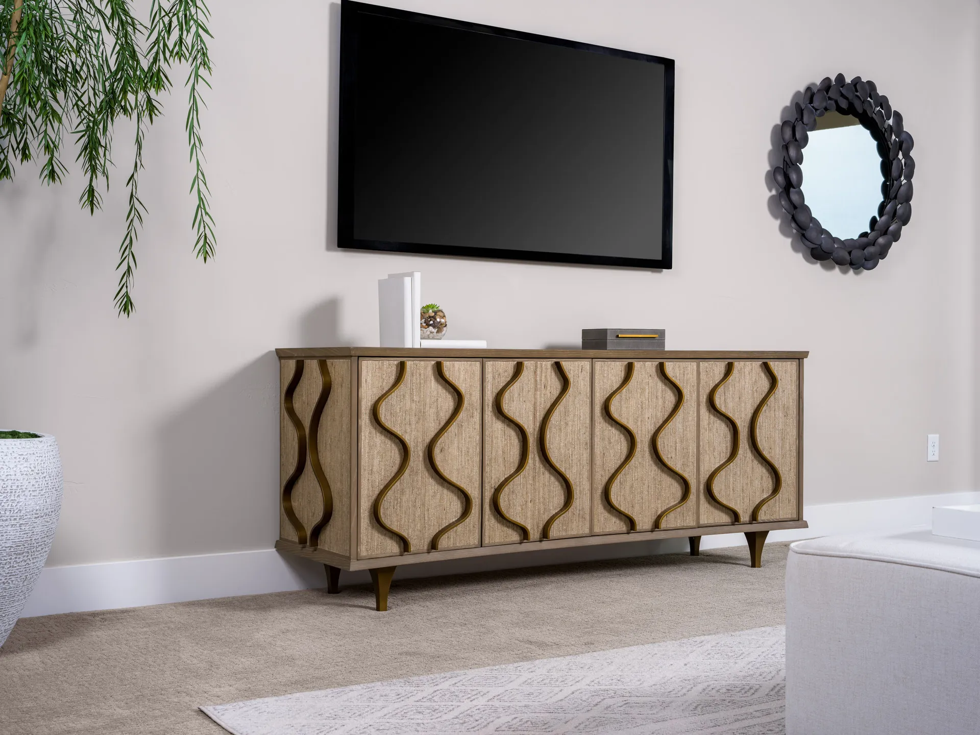 A wave-textured wooden console under a mounted TV, with a black circular mirror on the adjacent wall.