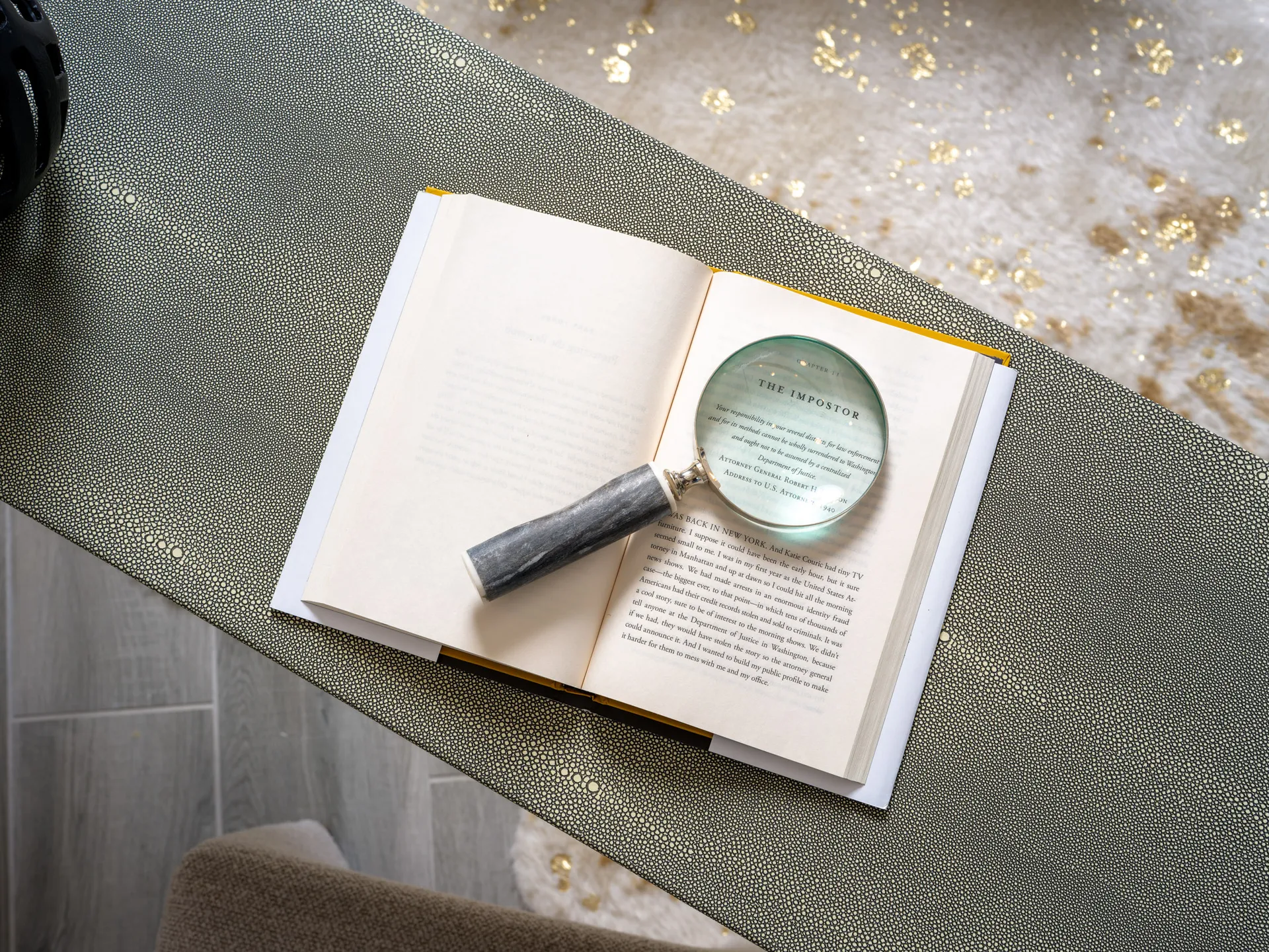 An open book with a magnifying glass placed on a textured surface, creating a cozy and luxurious reading ambiance.