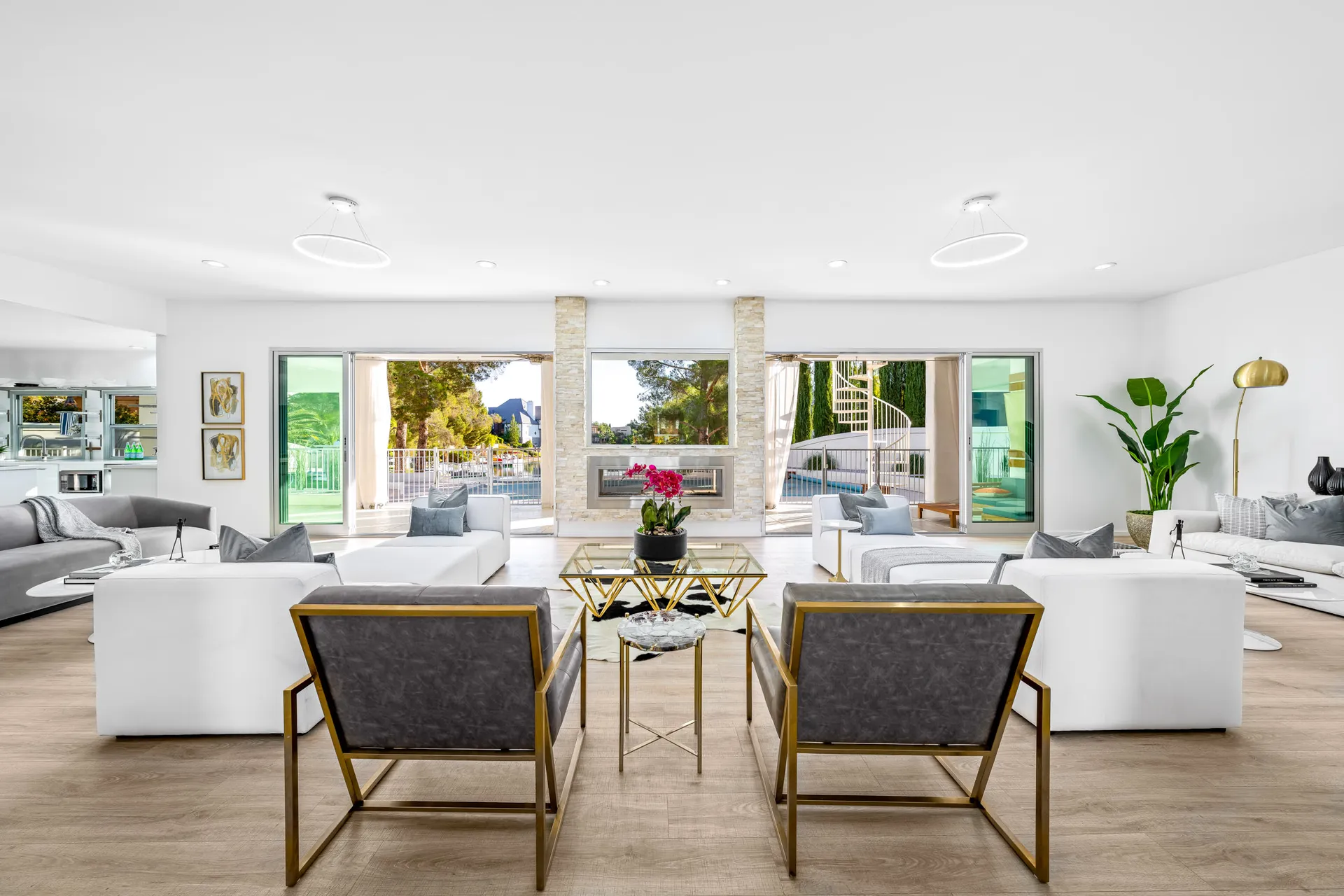 A bright living room with white and gray seating, a central fireplace, and large sliding doors leading to an outdoor area.