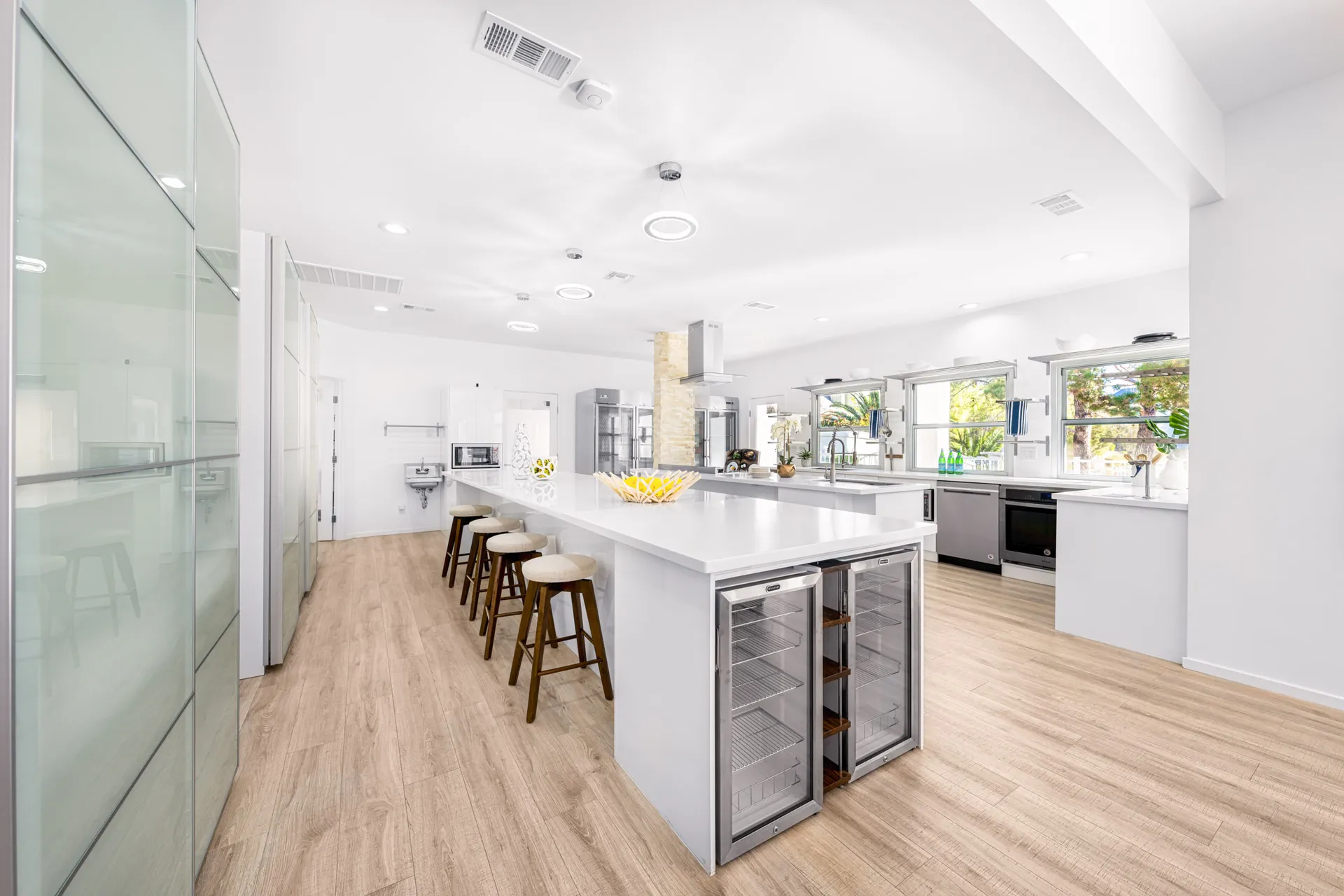 A bright, open-concept kitchen featuring a large island with bar stools, stainless steel appliances, and ample storage.