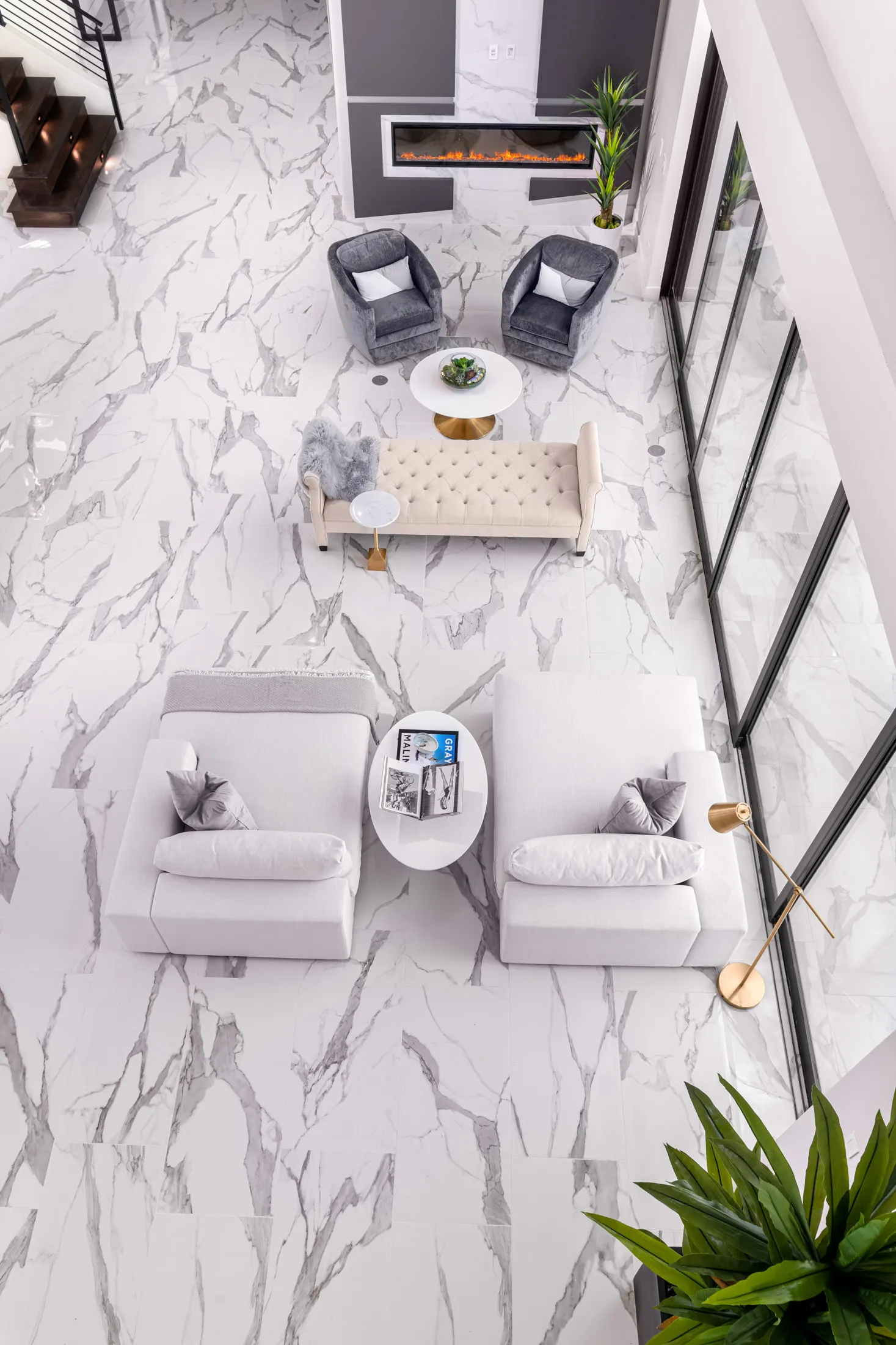 A modern living room with a white coffee table, a gray sofa, and a large window. The room features a neutral color palette and a minimalist design, creating a serene and inviting atmosphere.