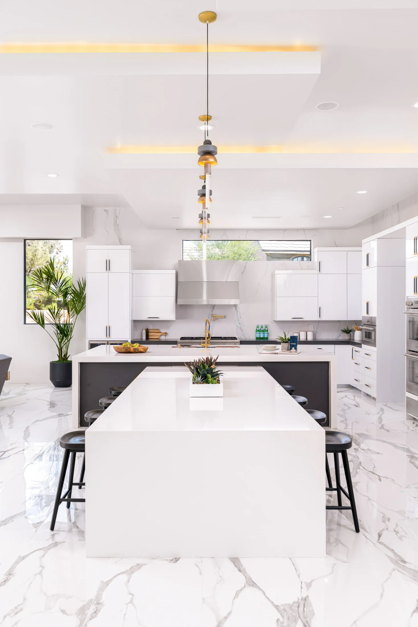 A modern kitchen with a large island, pendant lighting, and sleek white cabinetry. The design features a clean and minimalist aesthetic, creating a bright and open space.