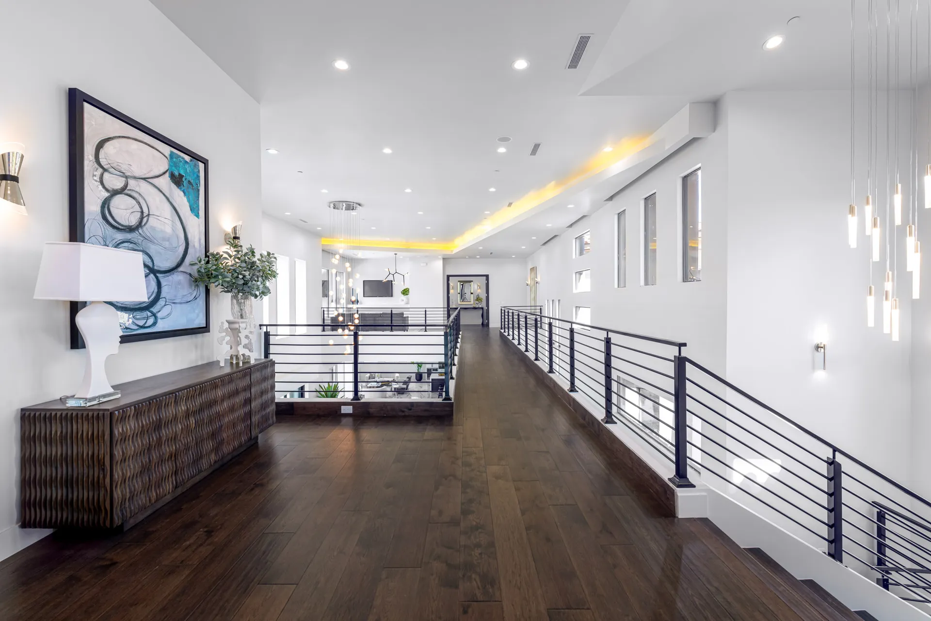 A loft area with a decorative console table, a modern chandelier, and a view of the outdoors. The design features a modern aesthetic with clean lines and a neutral color palette, creating a sophisticated and inviting atmosphere.
