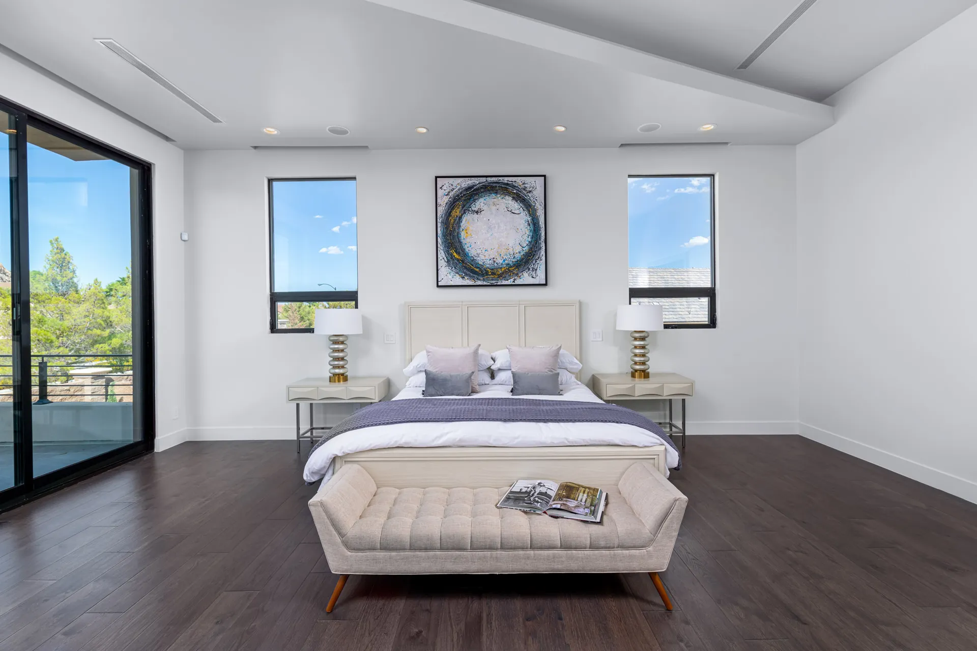 A master bedroom with a bed, a tufted bench, and a large abstract painting on the wall. The design features a modern aesthetic with clean lines and a neutral color palette, creating a serene and elegant atmosphere.