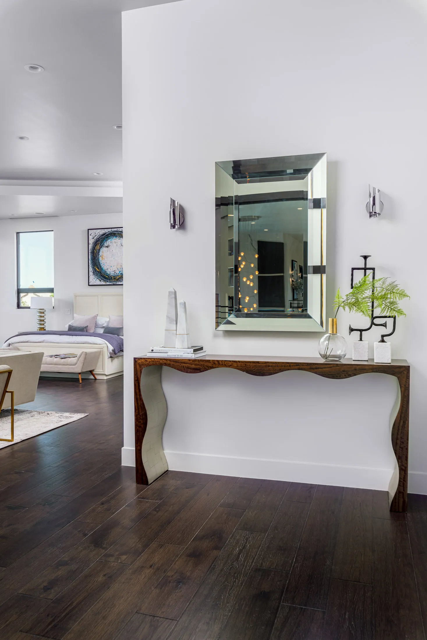 A bedroom with a bed, a tufted bench, and a large abstract painting on the wall. The design features a modern aesthetic with clean lines and a neutral color palette, creating a serene and elegant atmosphere.