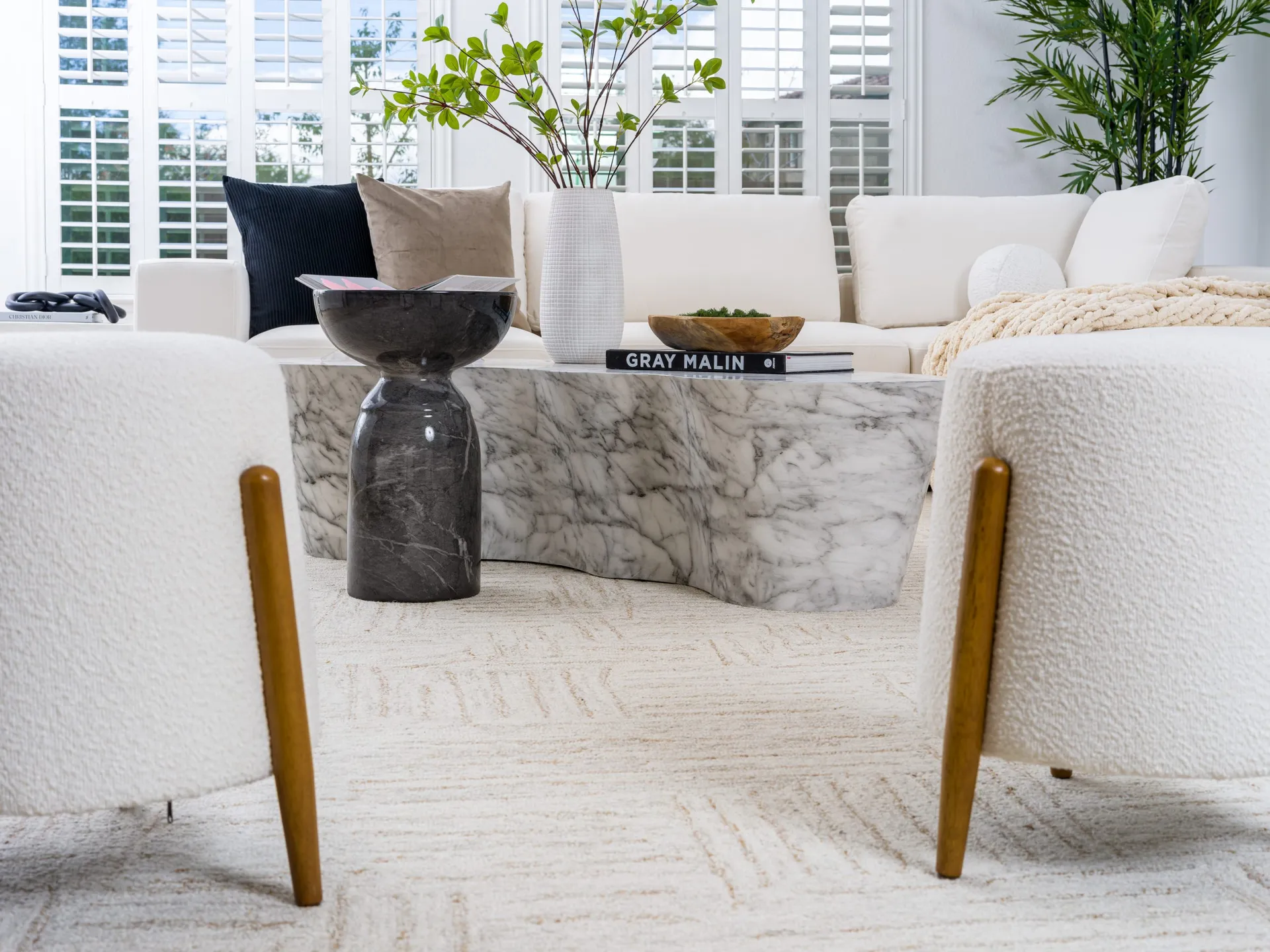 Modern living room with white sofa, marble coffee table, and green plants