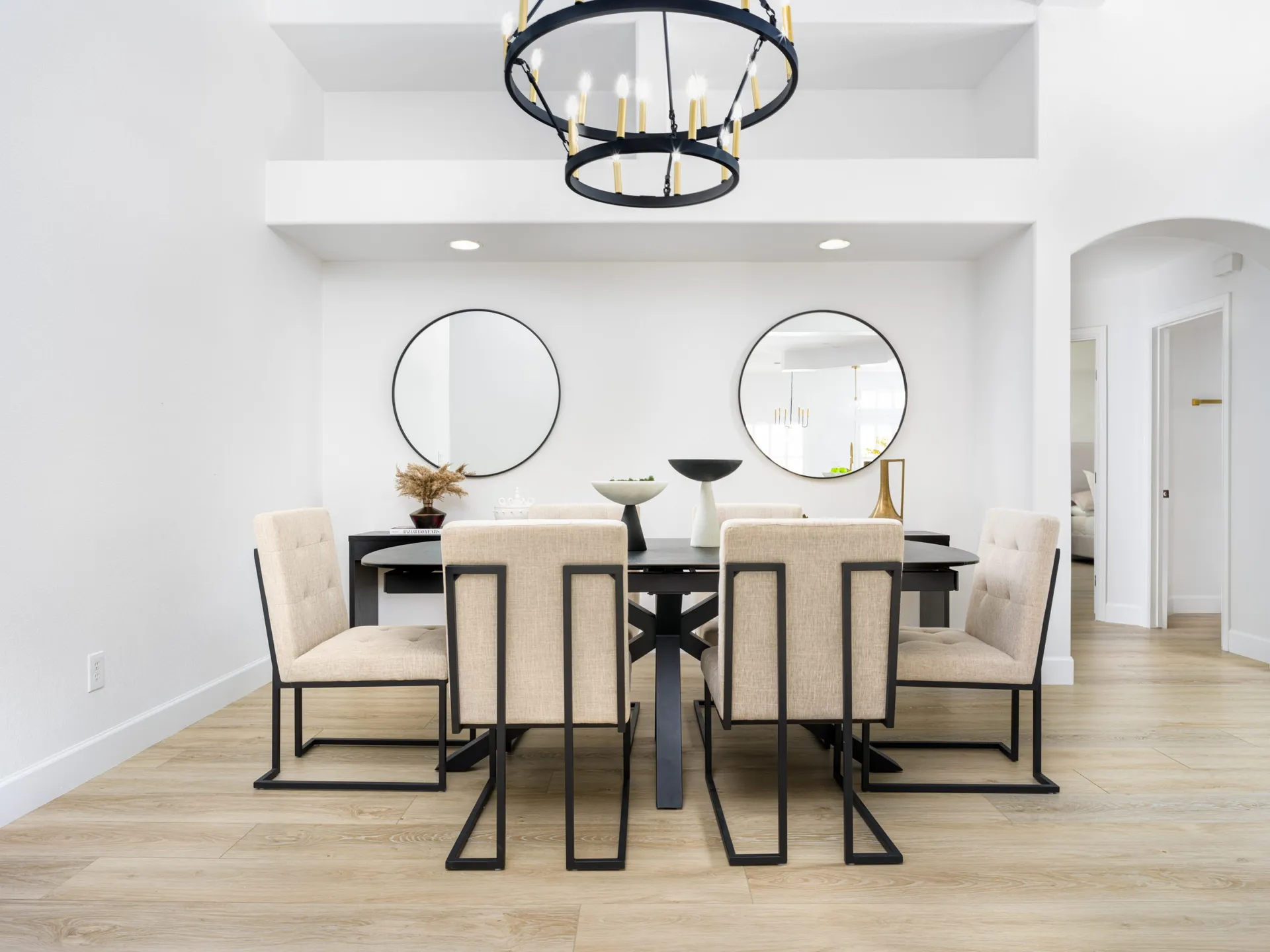 Modern dining room with large table, beige chairs, and round mirrors