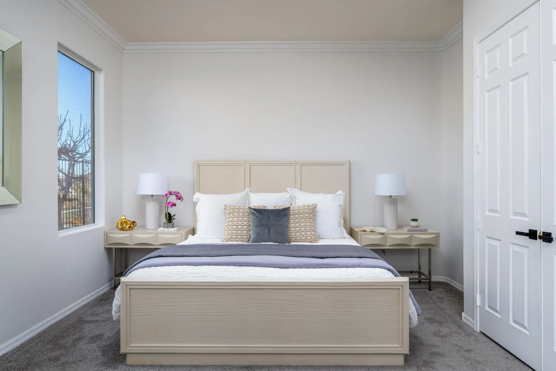 A serene bedroom with a light wood bed frame, plush bedding, matching nightstands, and soft neutral tones for a calming atmosphere.