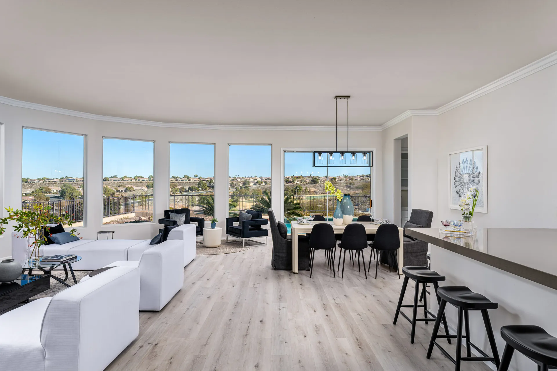 A modern open-concept living and dining space with panoramic windows, sleek furnishings, and a seamless flow between seating areas.