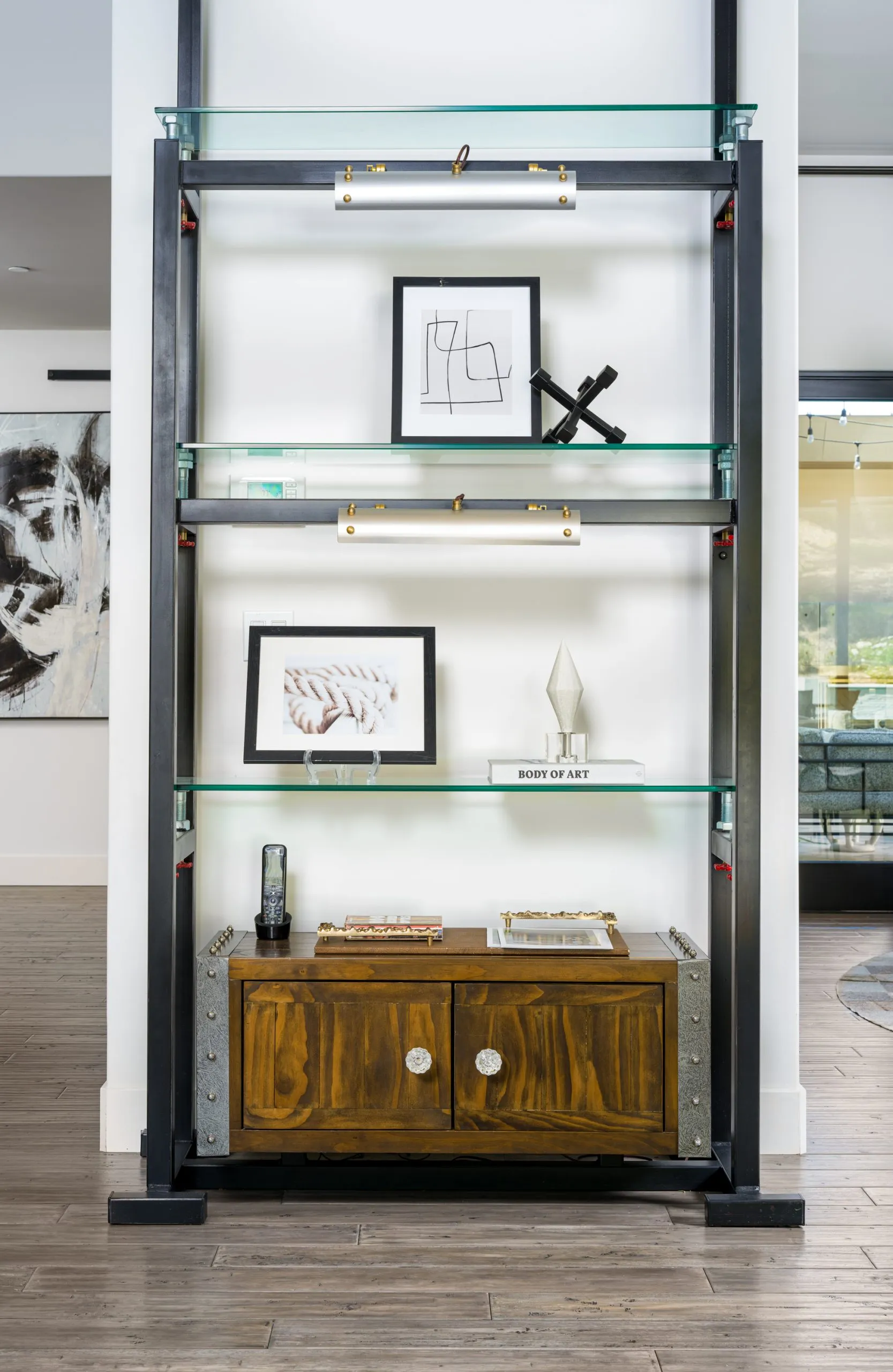 Modern shelving unit with glass shelves, wooden base, and decorative items