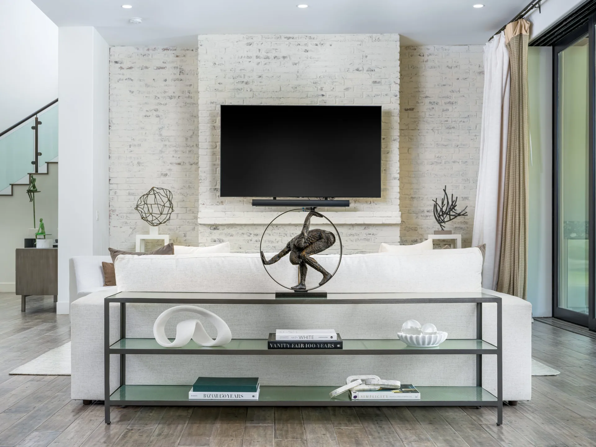 Modern living room with white sofa, glass coffee table, and flat-screen TV