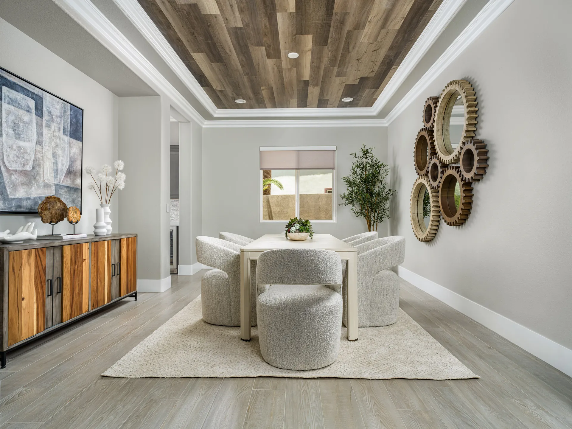 A modern dining room with a wood-paneled ceiling, a multi-tone console, and circular gear mirror accents on the wall.