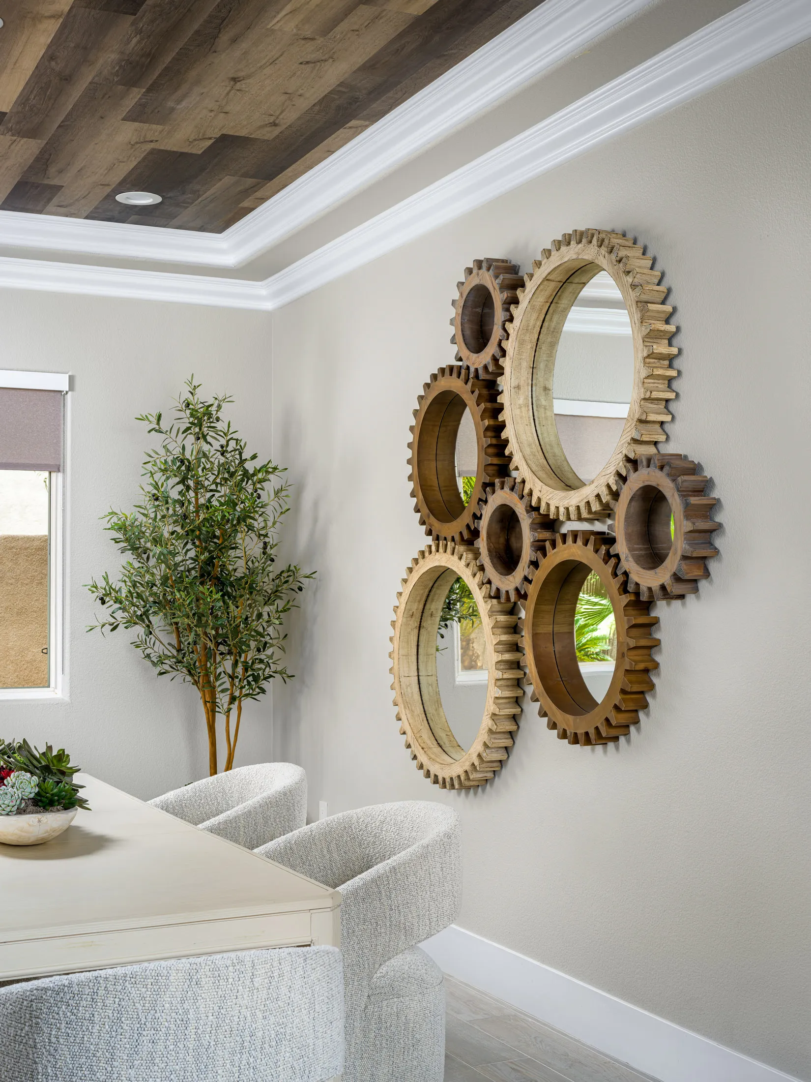 A dining area with circular wooden gear mirrors on the wall, textured chairs, and a wood-paneled ceiling.