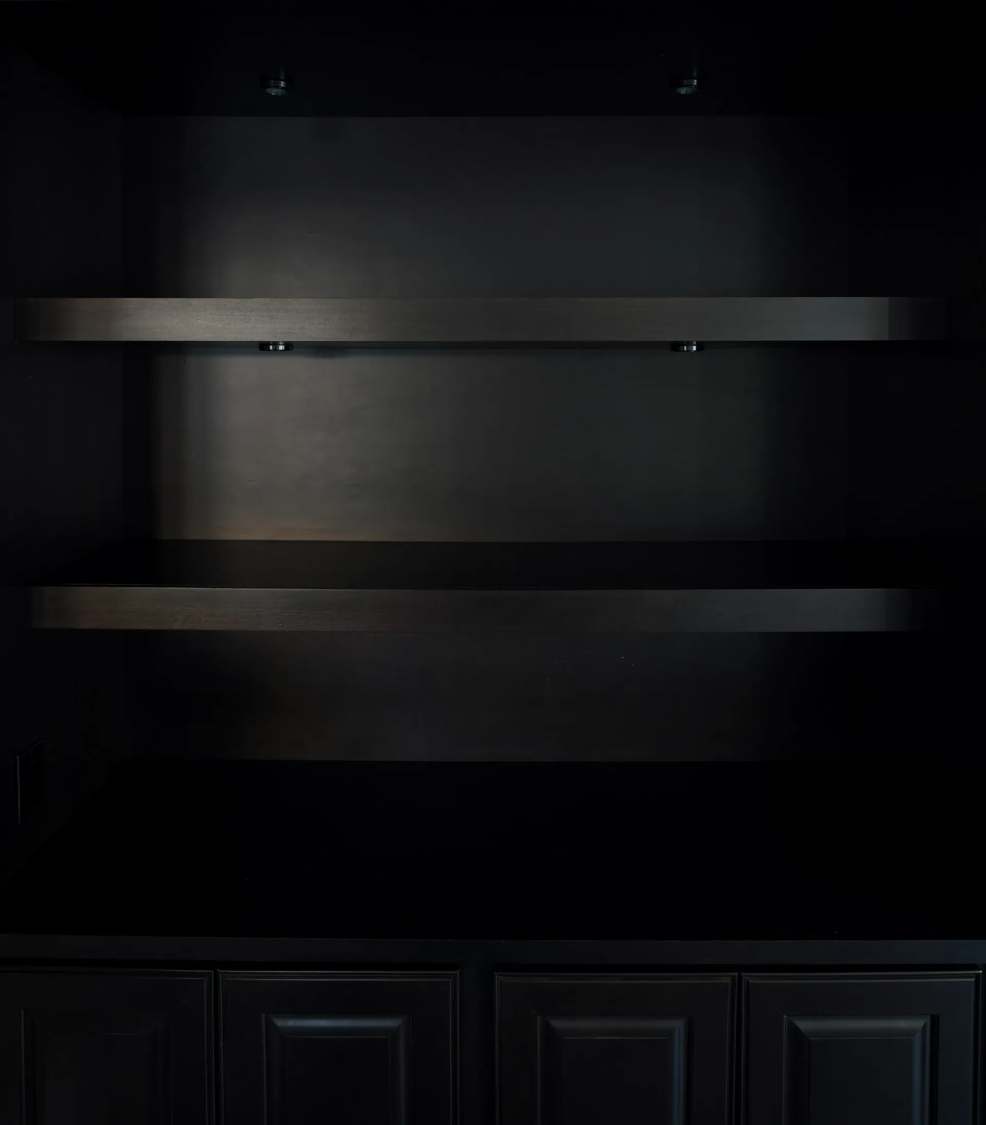 An empty black built-in shelving unit with floating shelves and lower cabinets.