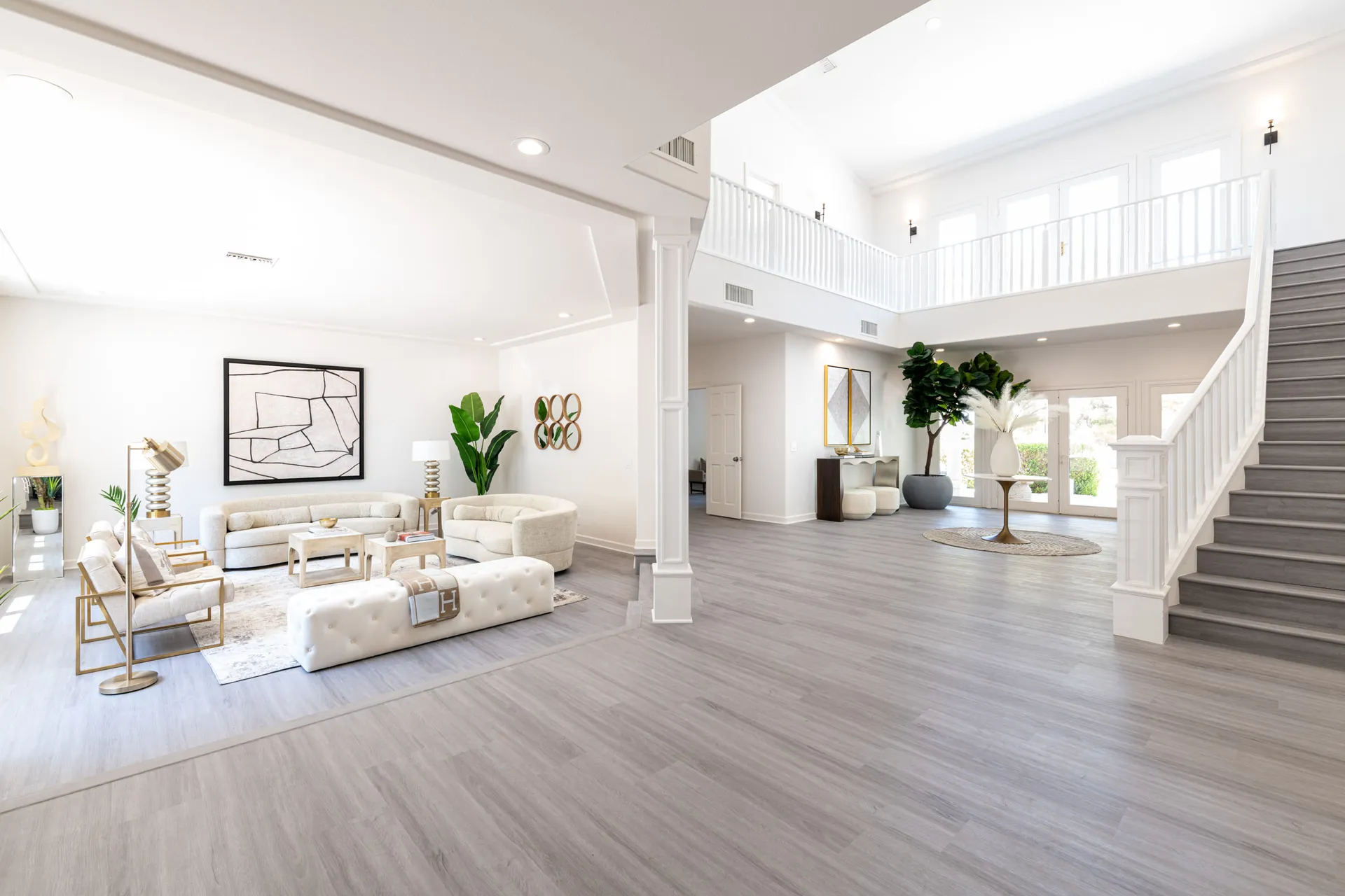 A bright entry space with neutral seating, a tufted bench, and a sweeping staircase.