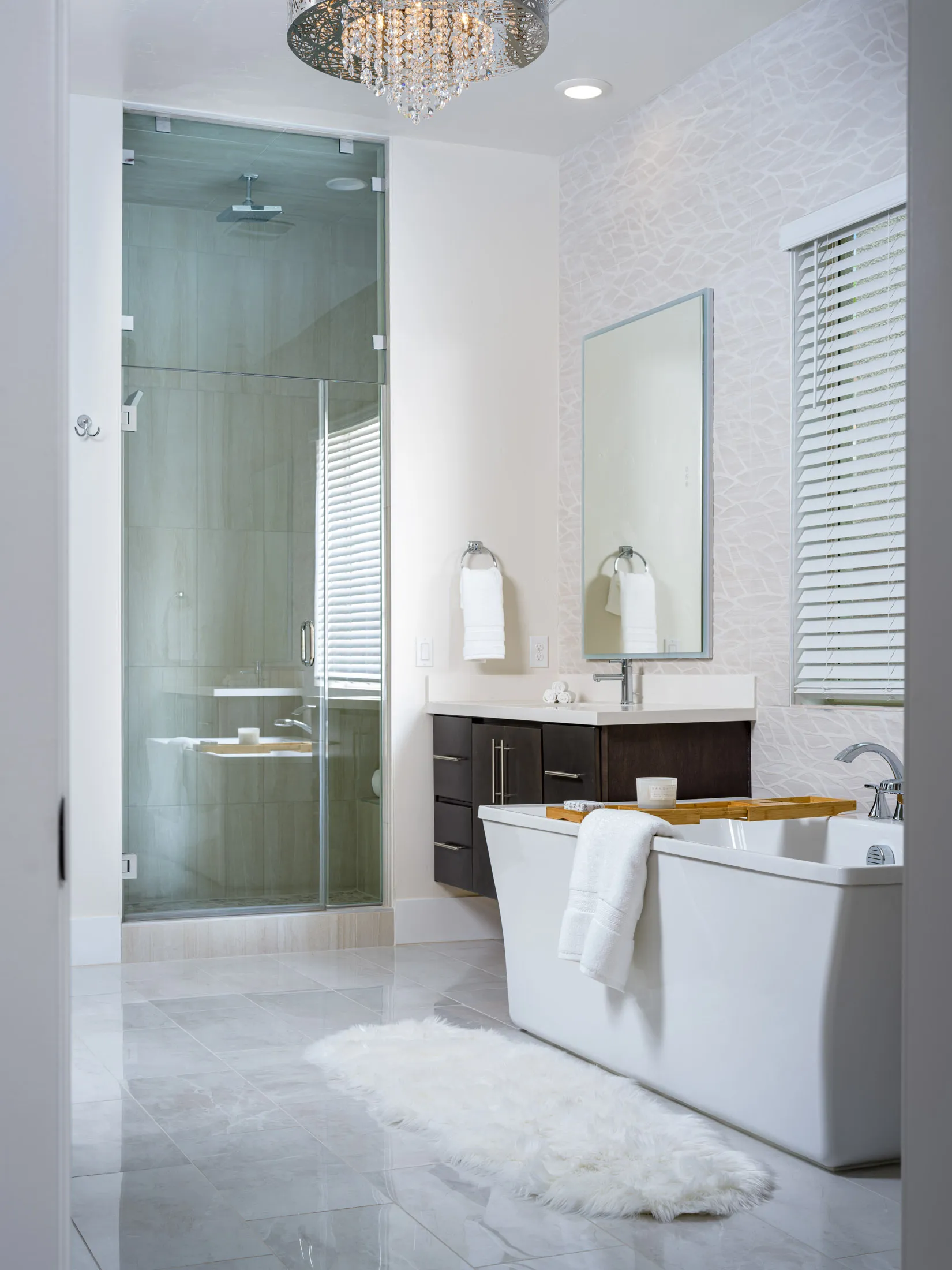 An elegant master bath with a glass-enclosed shower, soaking tub, and crystal chandelier. Staged by Stately in Las Vegas for a spa-like retreat.