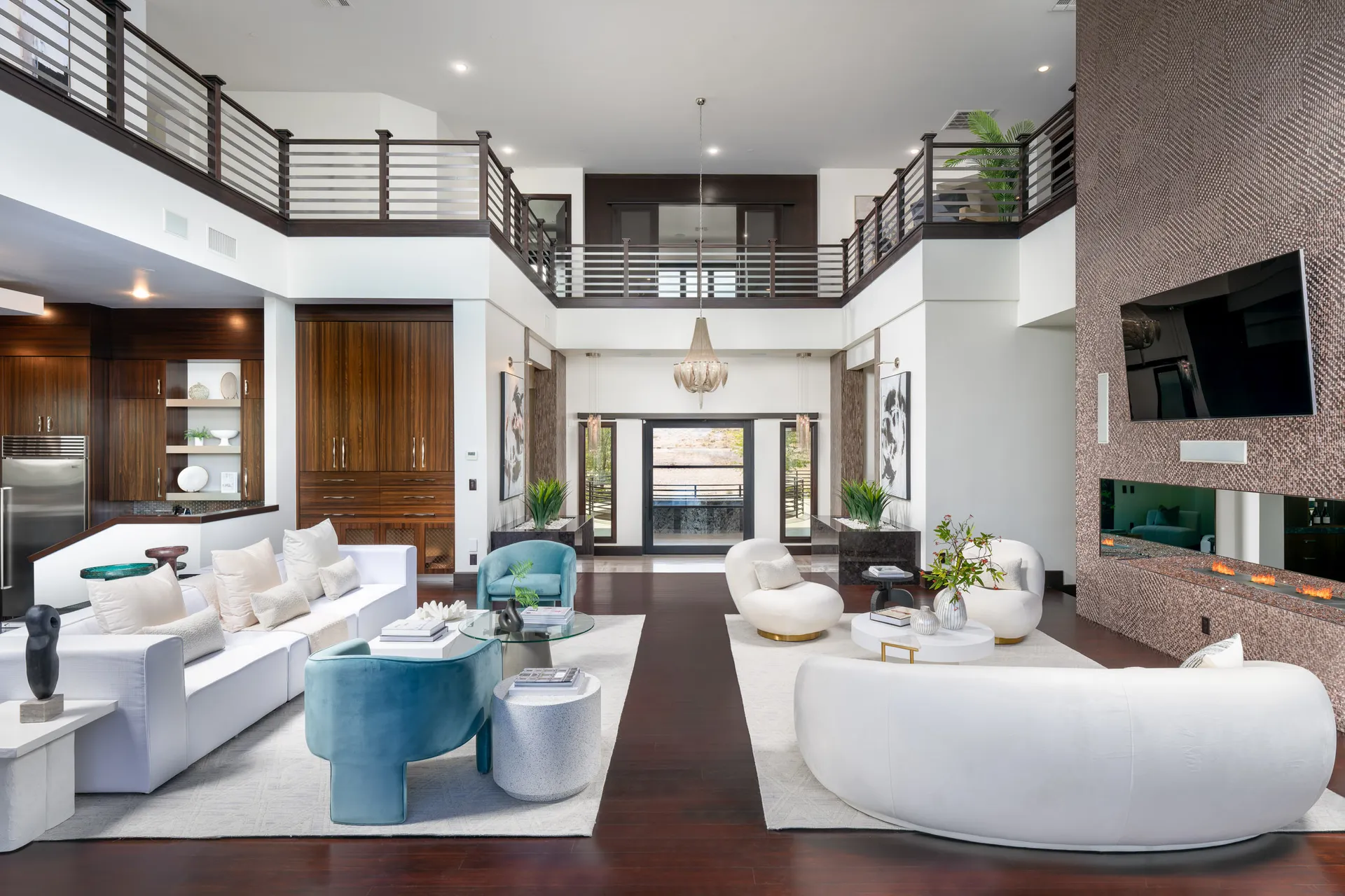 Spacious living room with high ceiling, modern furniture, and large wall-mounted TV.