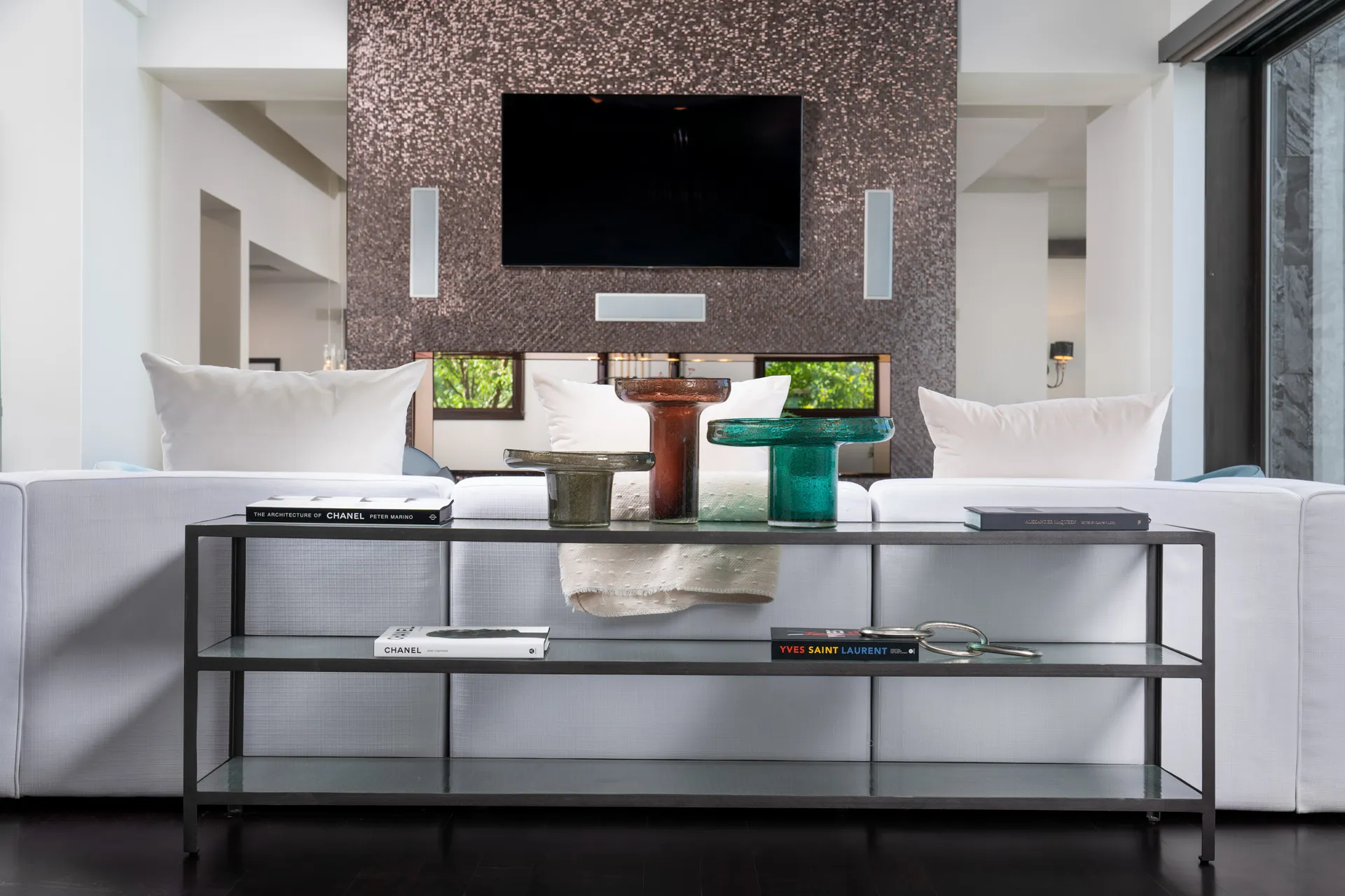 Modern living room with glass coffee table, wall-mounted TV, and textured accent wall.