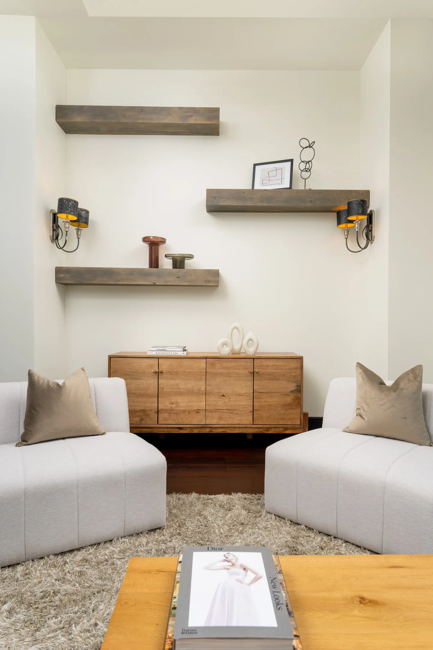 Cozy living room with wooden console table, floating shelves, and comfortable seating.
