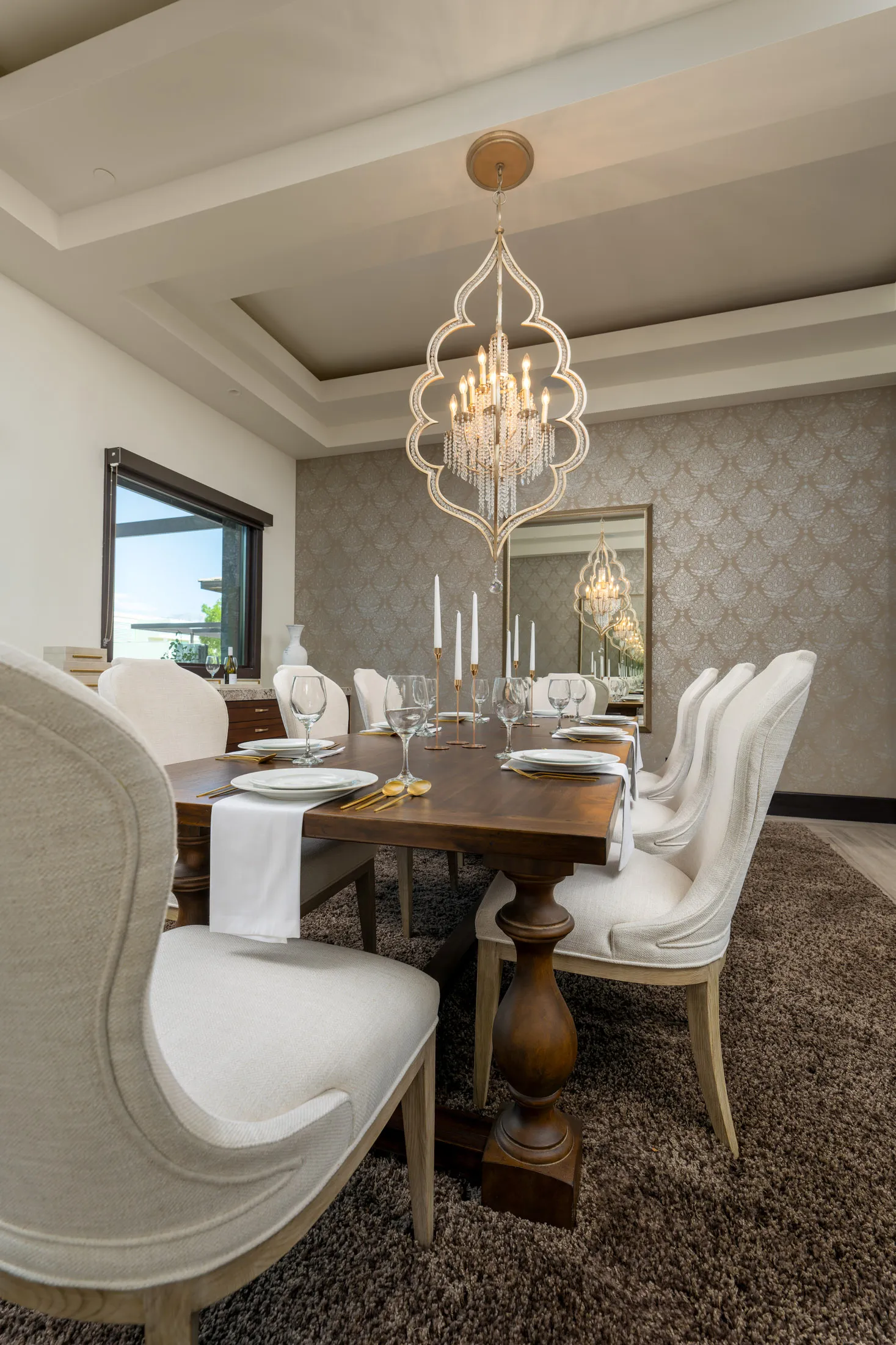 Elegant dining room with wooden table, upholstered chairs, and chandelier.