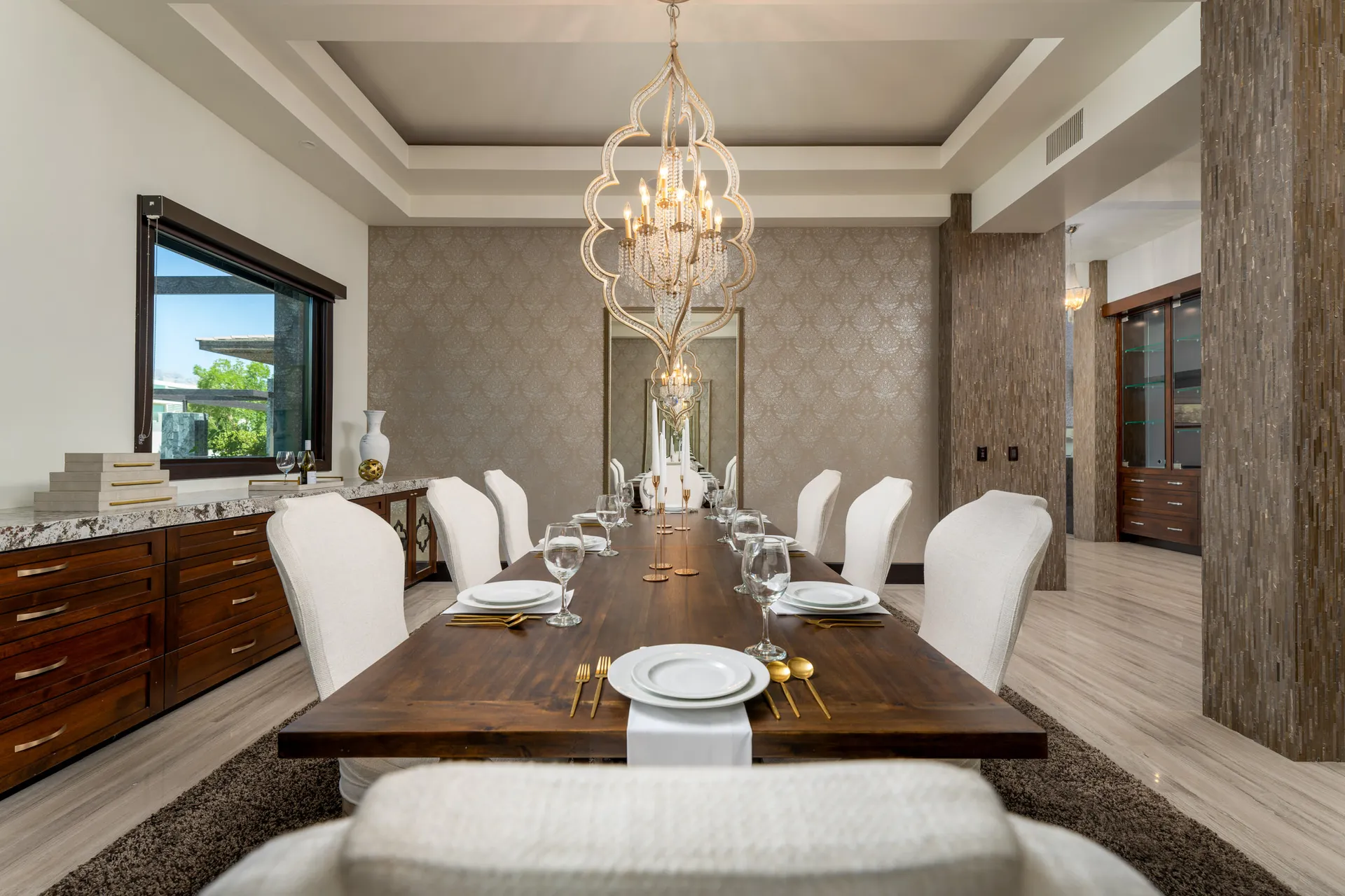 Elegant dining room with wooden table, upholstered chairs, and chandelier.