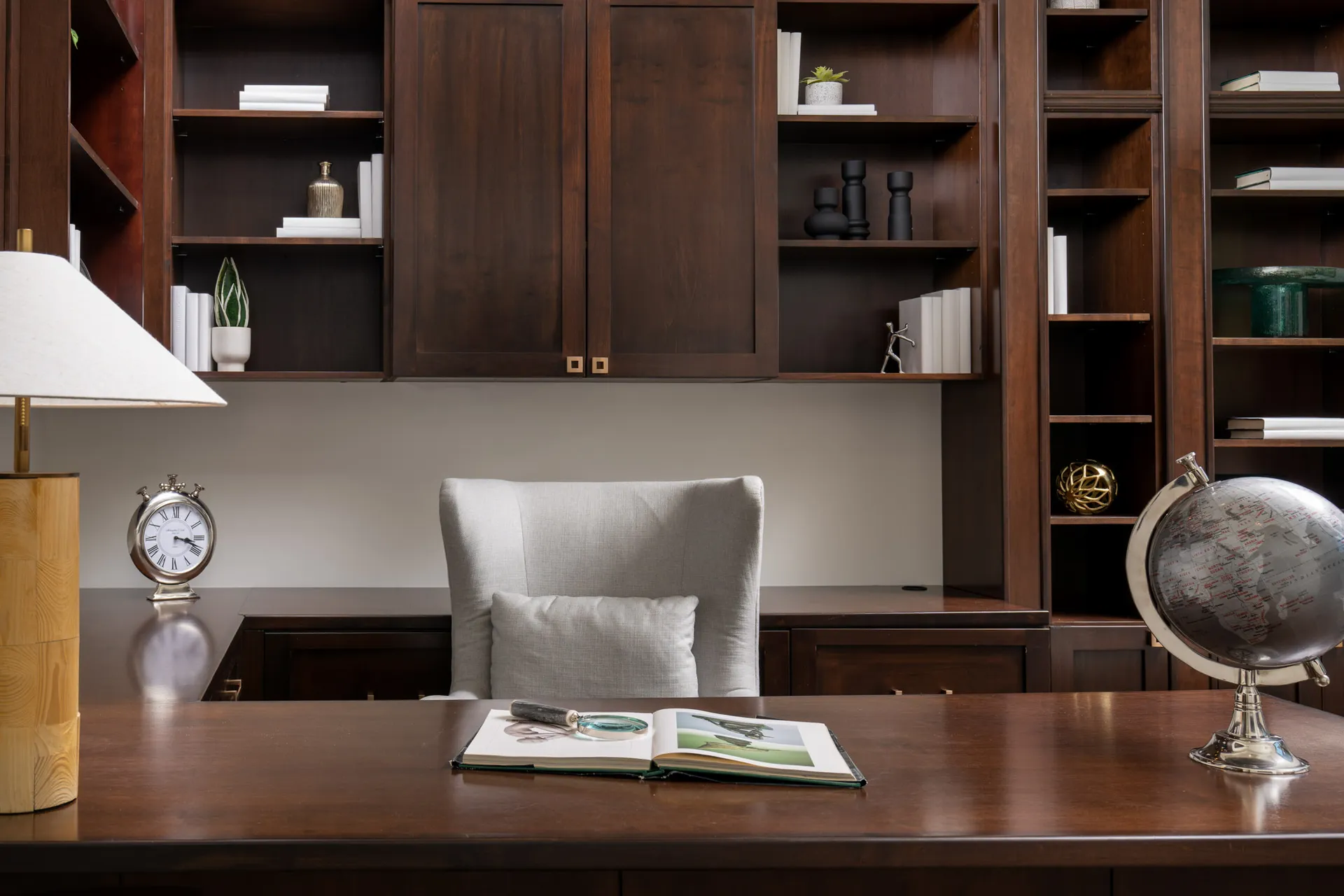 Luxurious home office with large wooden desk, bookshelves, and elegant decor.