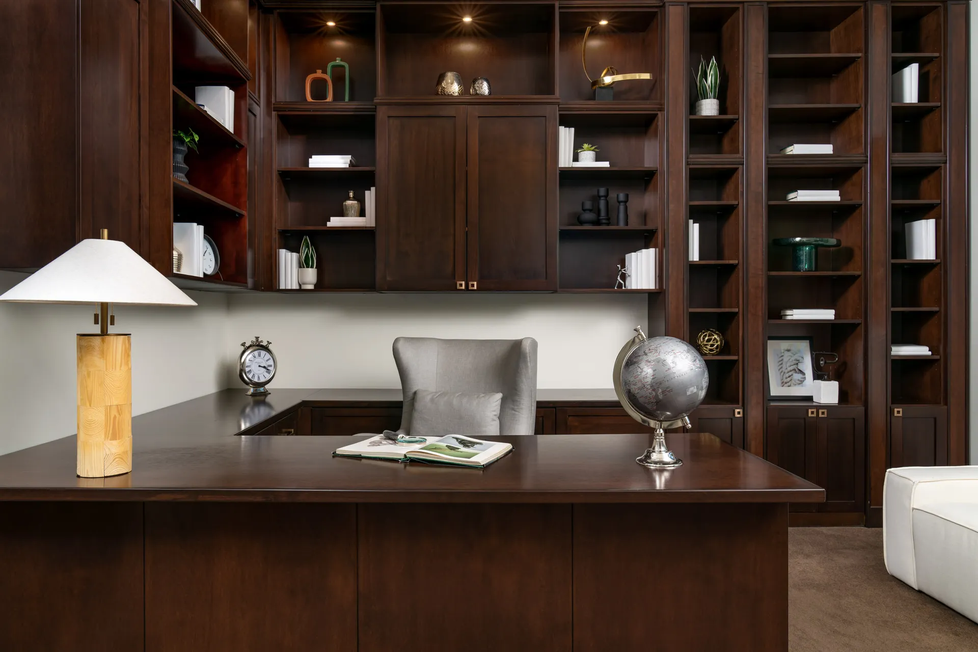 Luxurious home office with large wooden desk, shelves, and elegant decor.