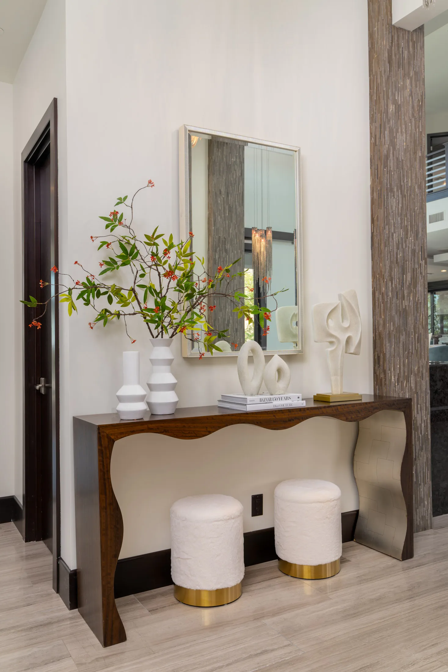 Modern hallway with wooden console table, large mirror, and decorative items.