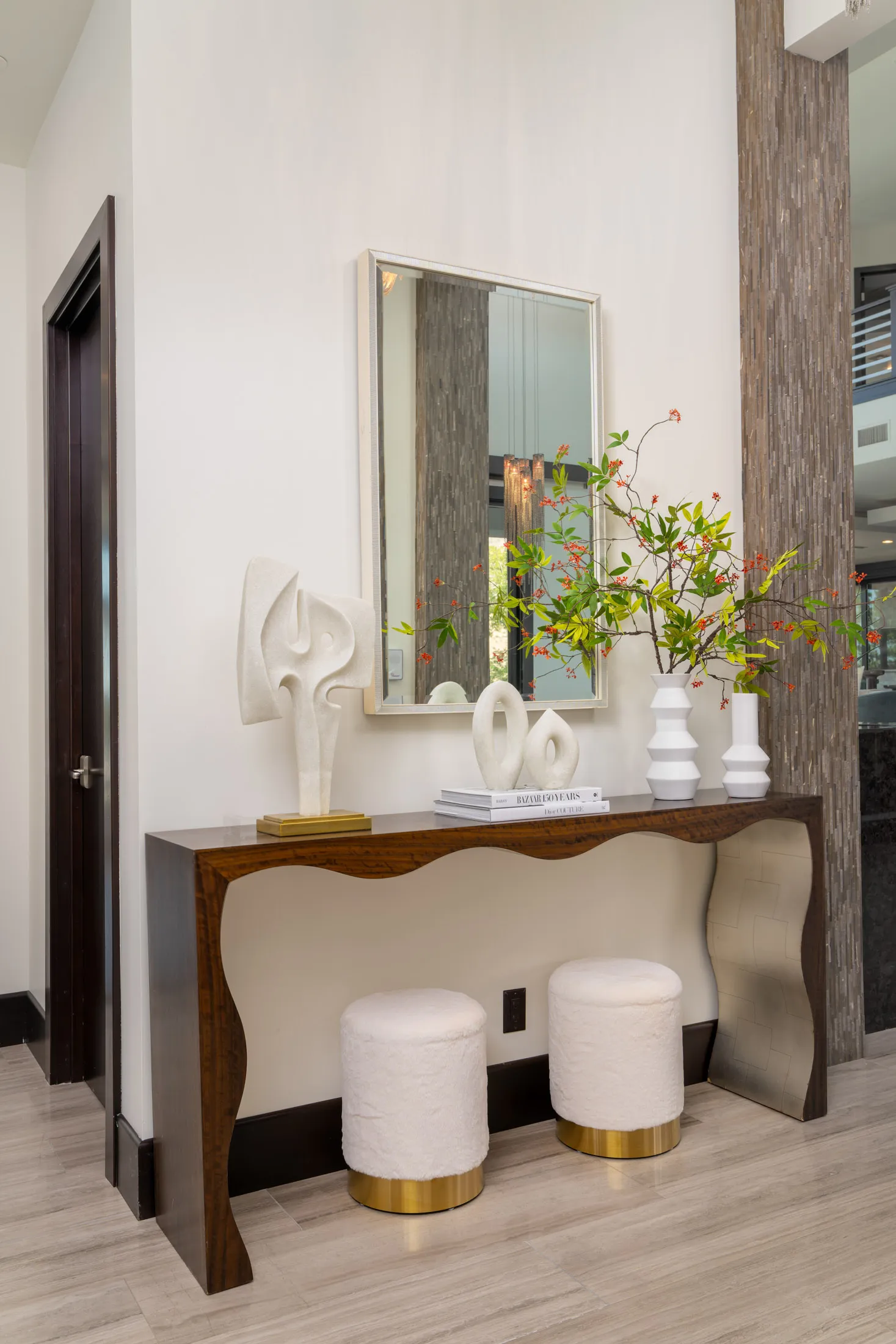 Modern hallway with wooden console table, large mirror, and decorative items.