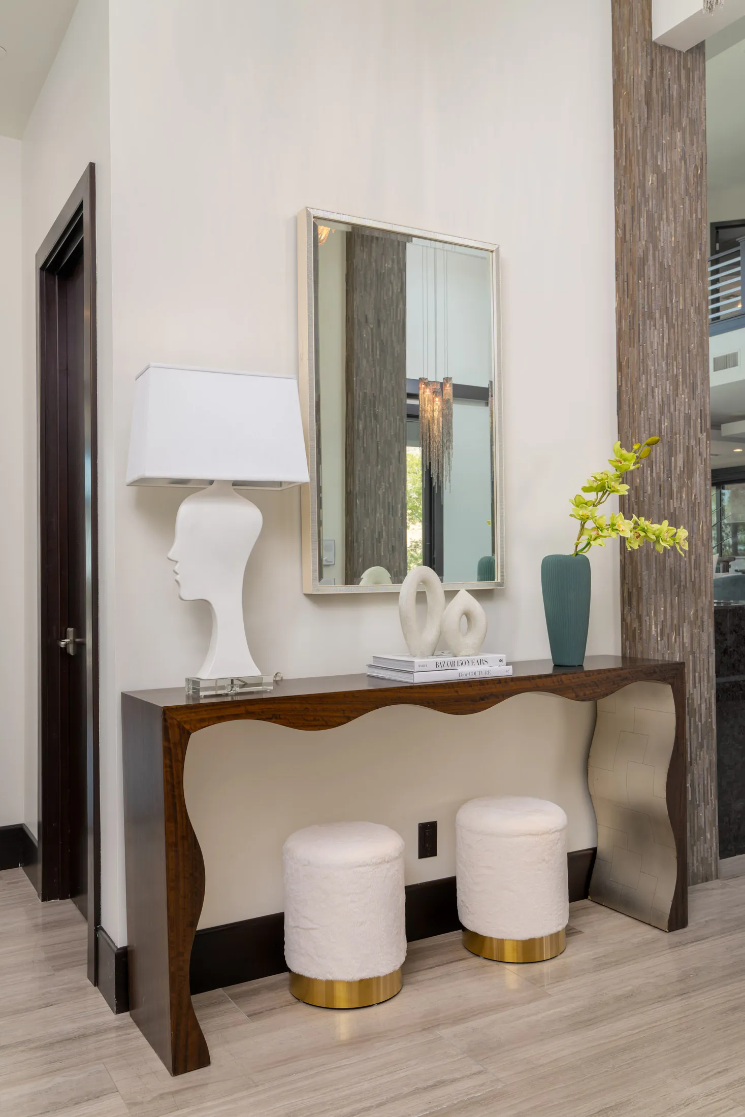 Hallway with wooden console table, large mirror, and stools with gold accents.