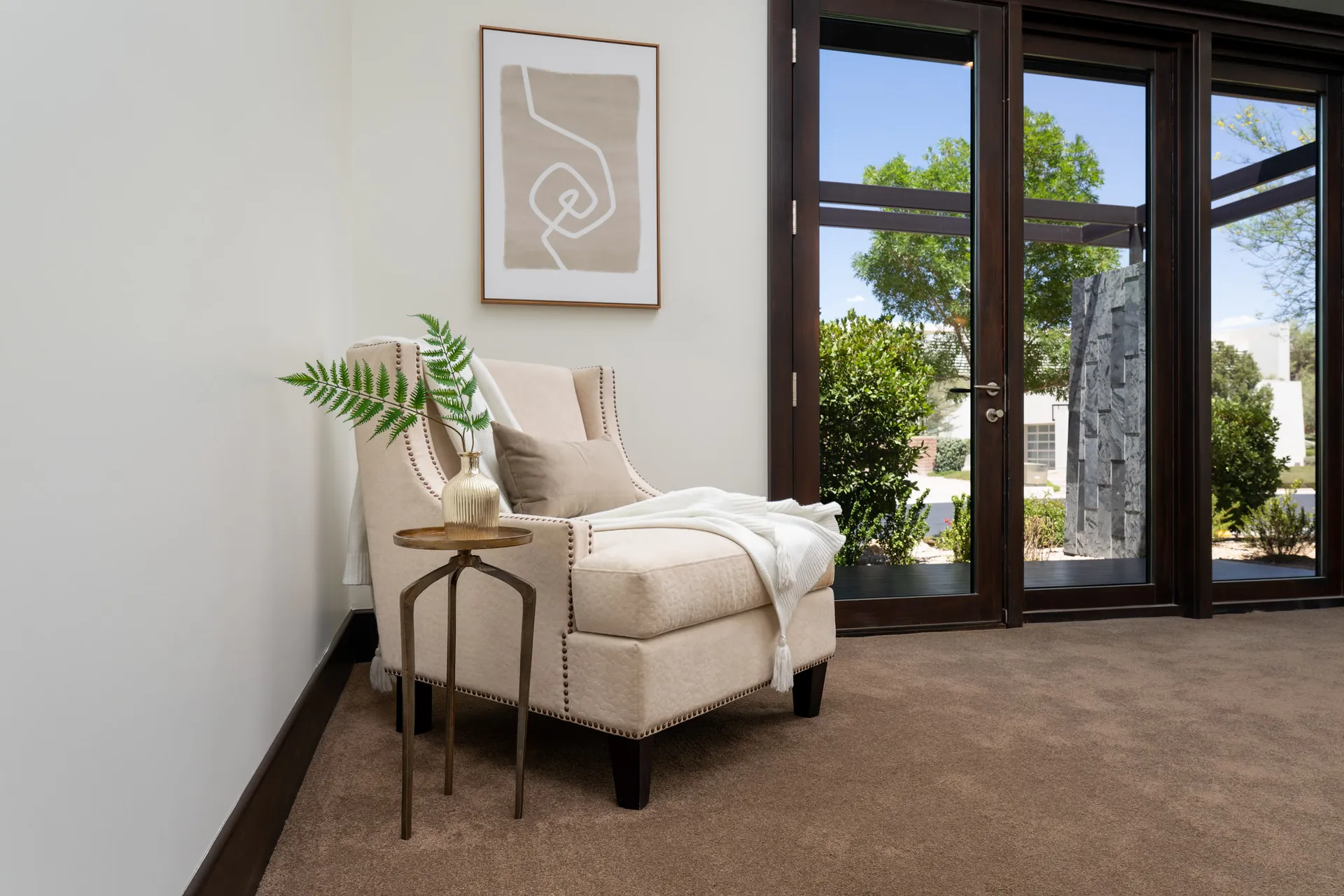 Cozy corner with beige armchair, side table, and wall art.