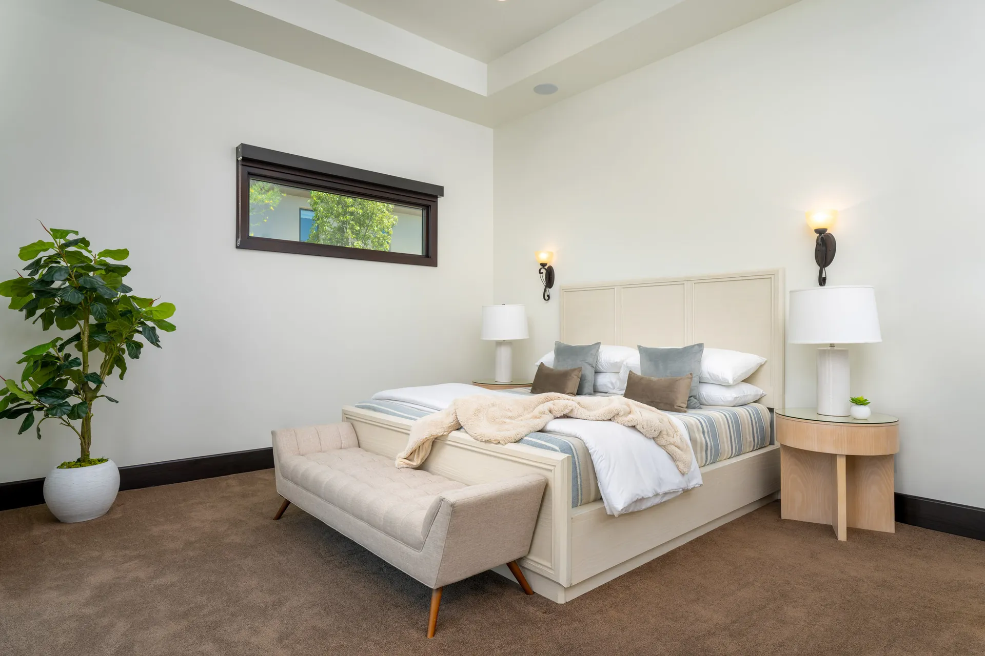 Minimalist bedroom with large bed, bench, and neutral color palette.