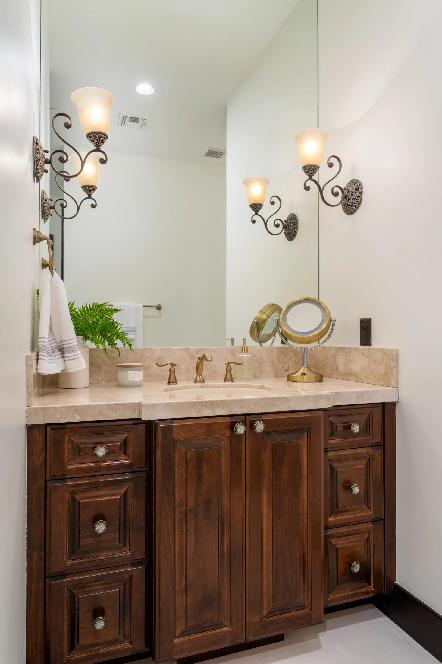 Bathroom with wooden vanity, marble countertop, and large mirror.