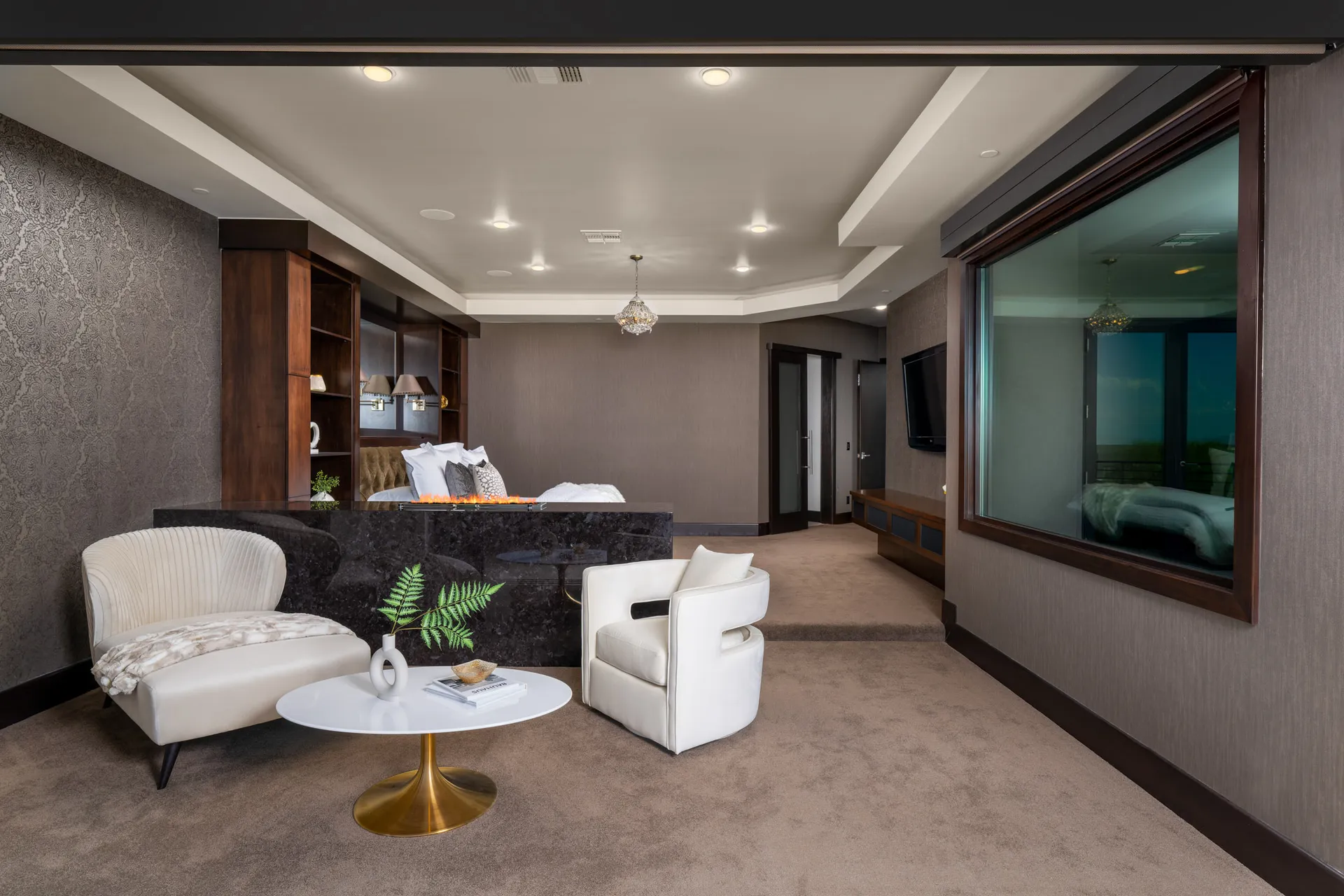 Luxurious bedroom with large bed, plush pillows, chandelier, and outdoor view.
