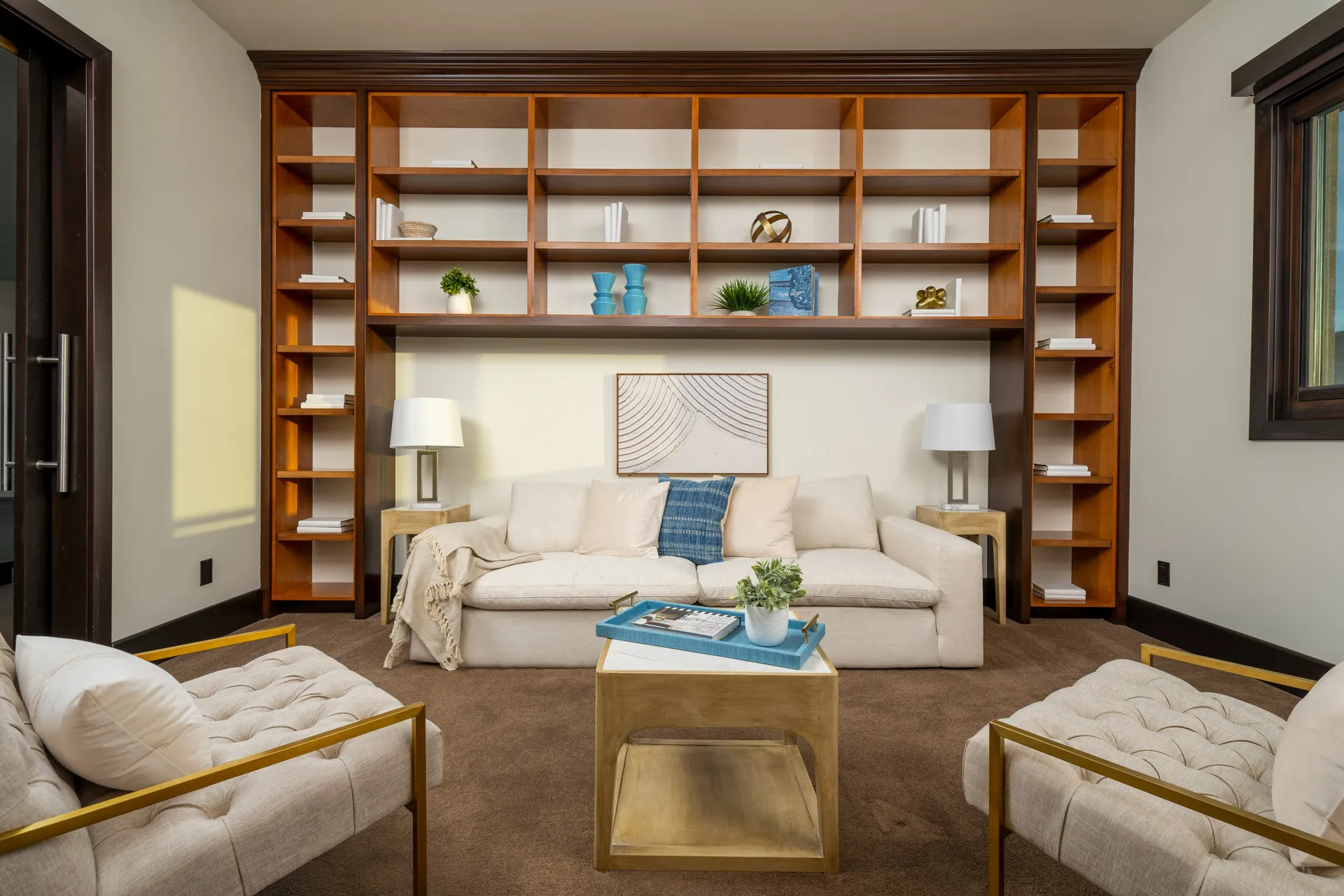 Stylish living room with beige sofa, blue throw blanket, marble coffee table, and wooden bookshelf.