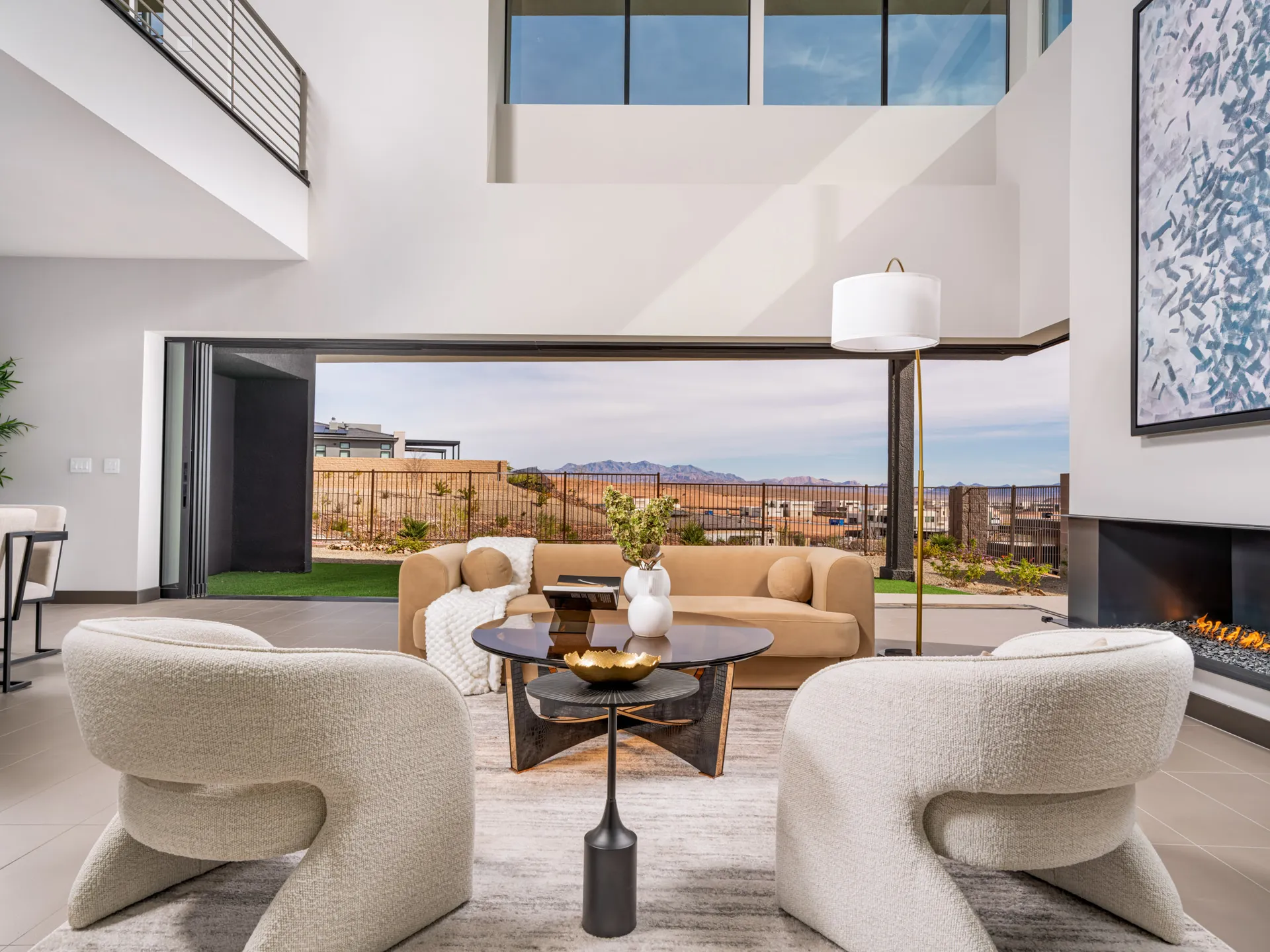 An open living area with a tan sofa, sculptural chairs, and large sliding doors revealing desert views.