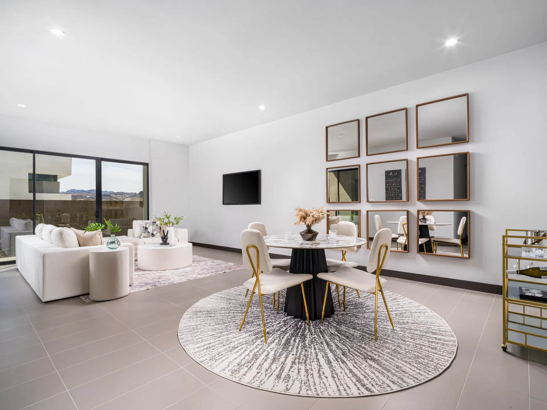 A bright, open entertainment area featuring a round table, gold chairs, and a plush white sectional near large sliding doors.
