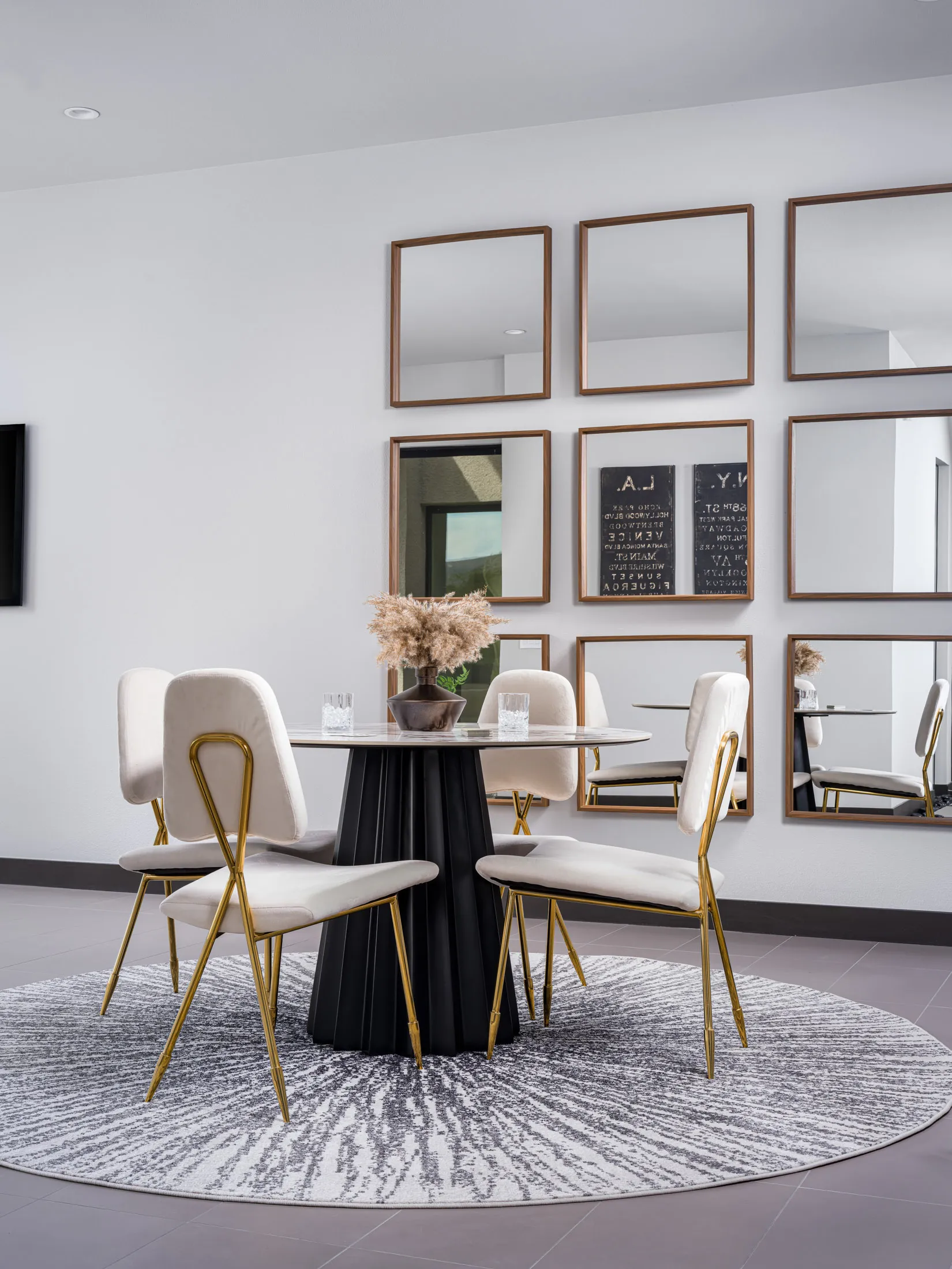 A round black table with velvet chairs on a circular rug, set before a wall of mirrors.