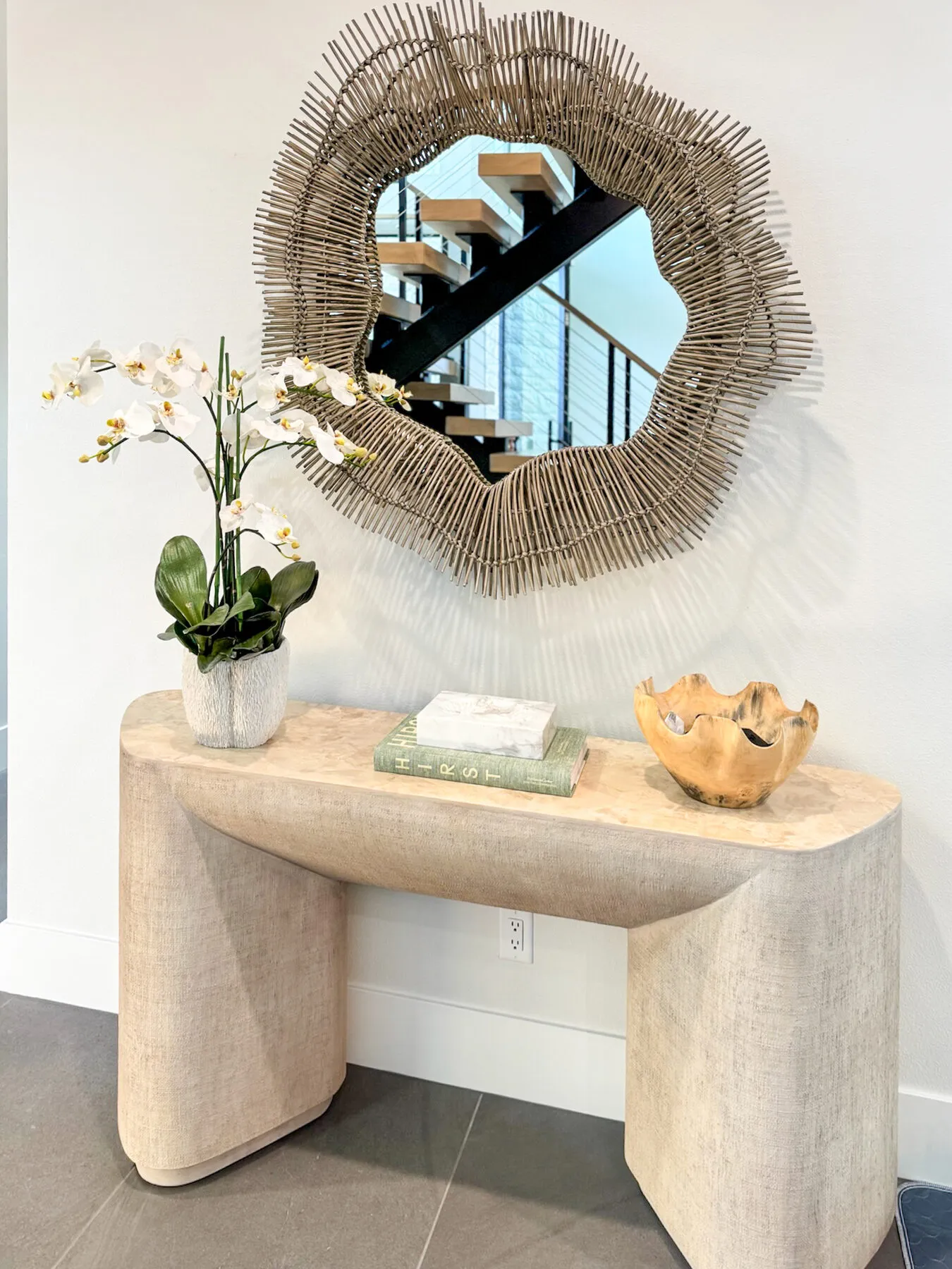 Curved Linen Console Beneath a Rattan Starburst