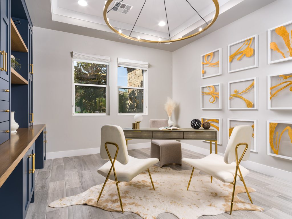 Luxury home office with gold accents, abstract wall art, and elegant blue cabinetry staged with modern furniture.