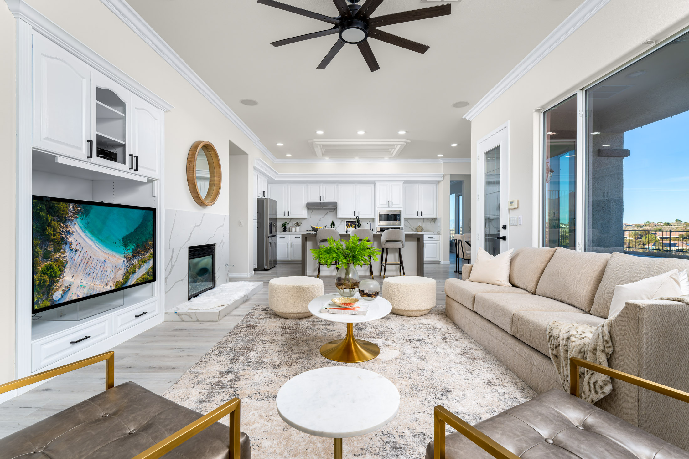 Oliver Springs Staging - A spacious living area with a large tan sofa, fireplace, and built-in white cabinetry leading into an open kitchen.