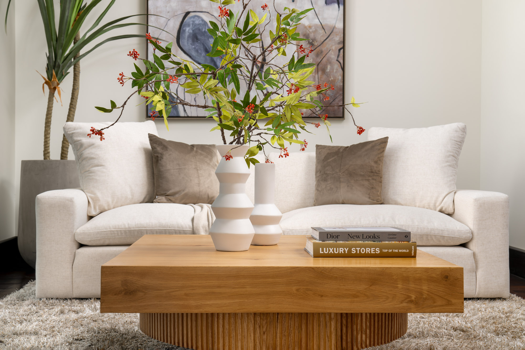 Living room with wooden coffee table, vase with flowers, and beige sofas.