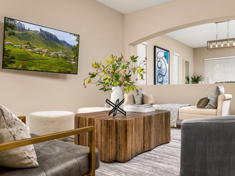Grand Opulence Home Staging highlighting a cozy living area with neutral furniture, a rustic wood coffee table, and a wall-mounted TV.
