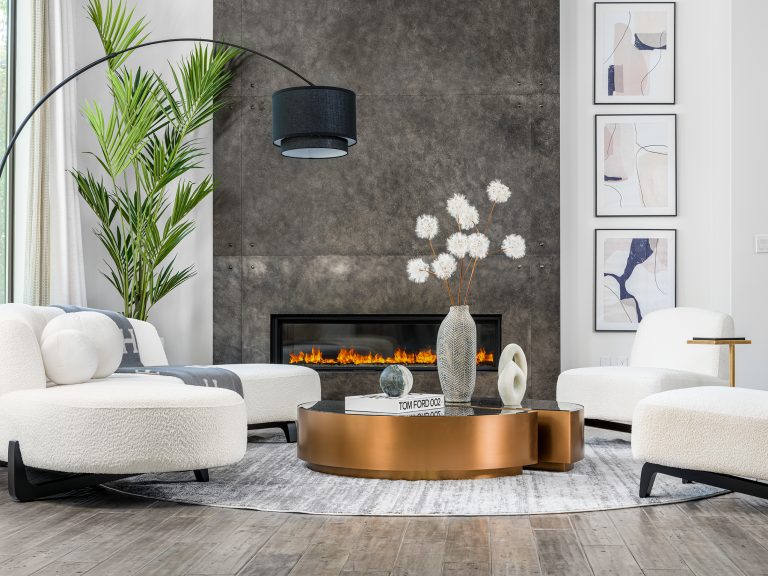 Stylish living room setup featuring a bronze coffee table, plush white chairs, a modern arc lamp, and an accent fireplace with a textured wall. A refined example of Modern Luxury Home Staging by Stately.